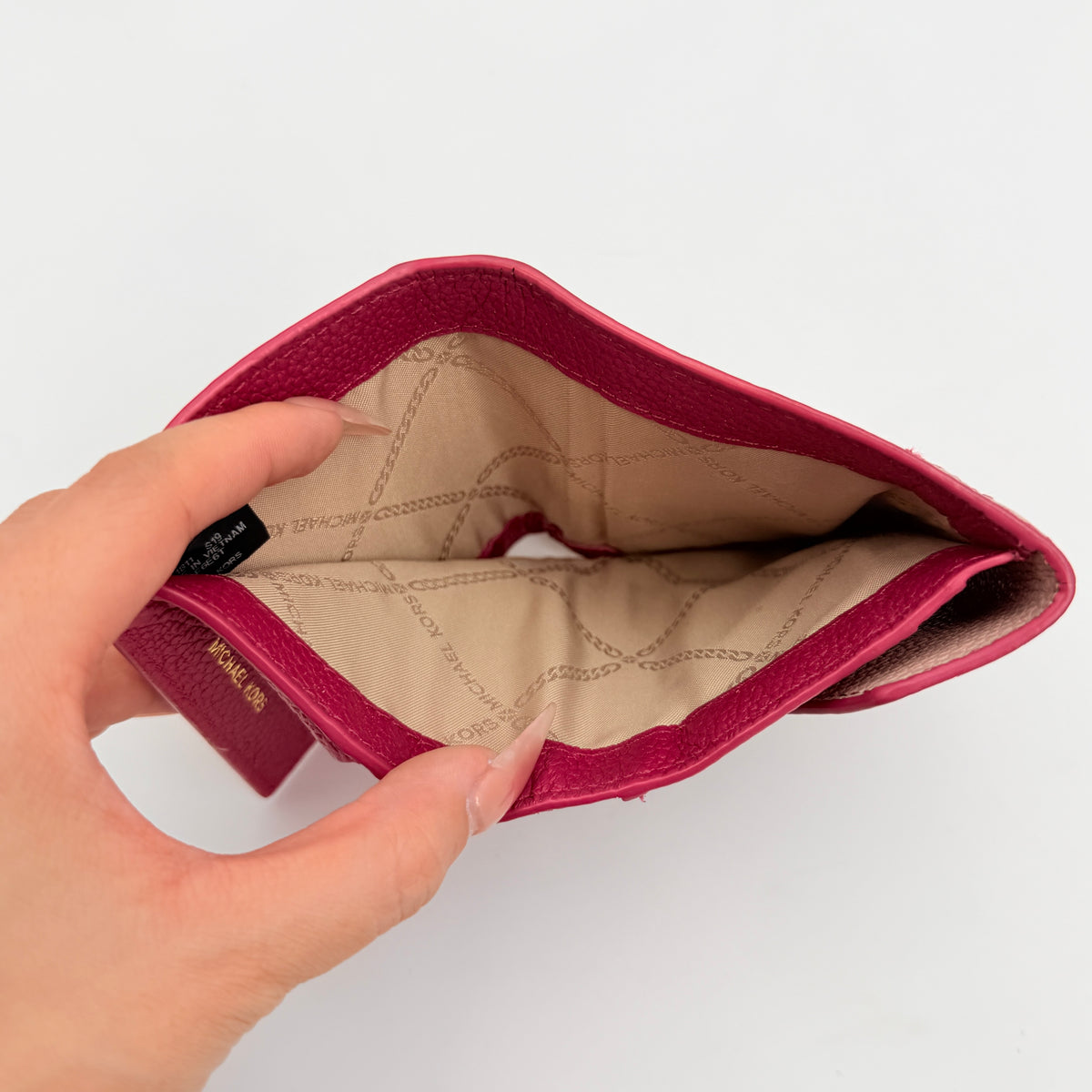 Michael Kors pink leather envelope trifold wallet with gold MK logo, shown closed on a white background.