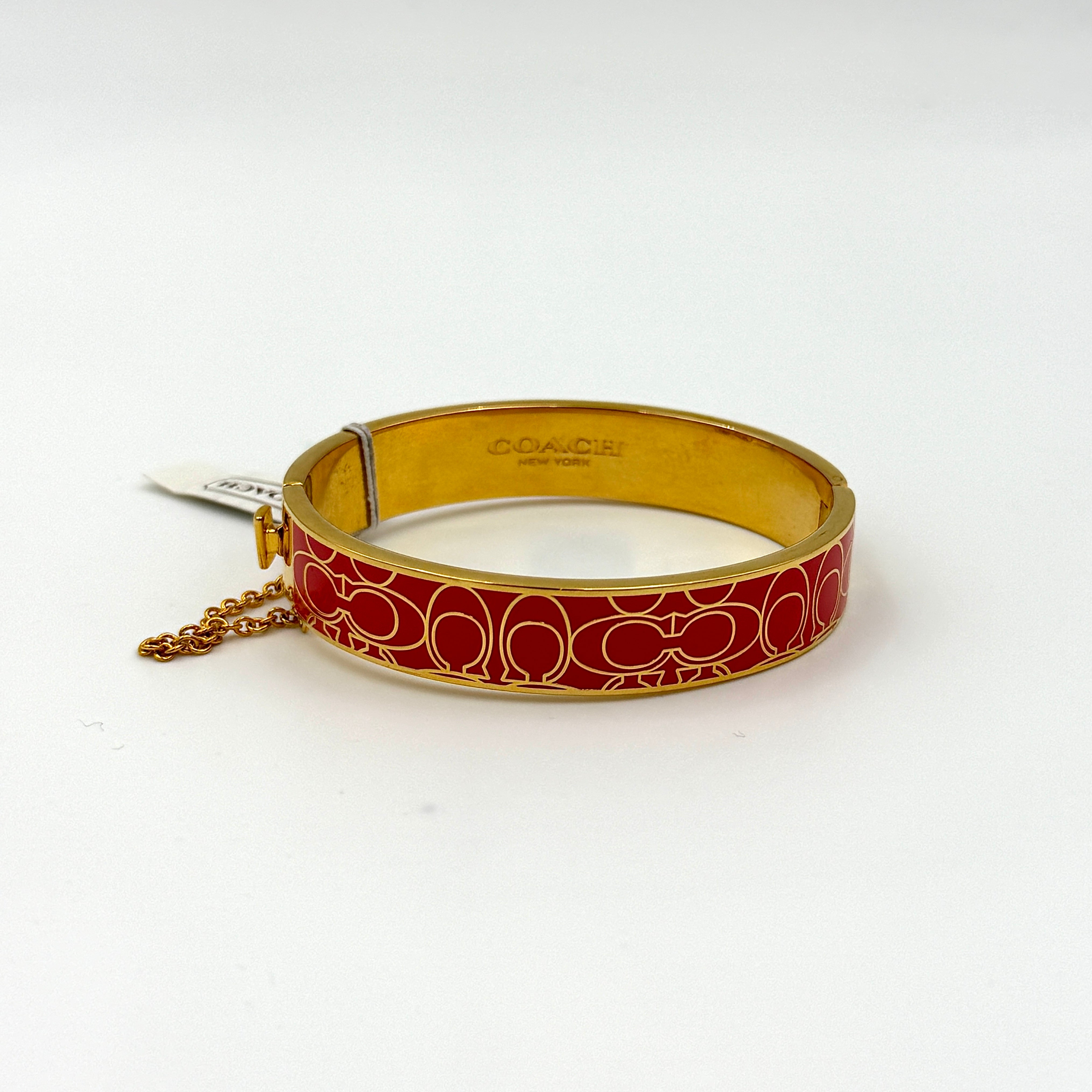 Coach Signature C Bangle Bracelet in gold-tone metal with red enamel, featuring the signature C motif and safety chain.