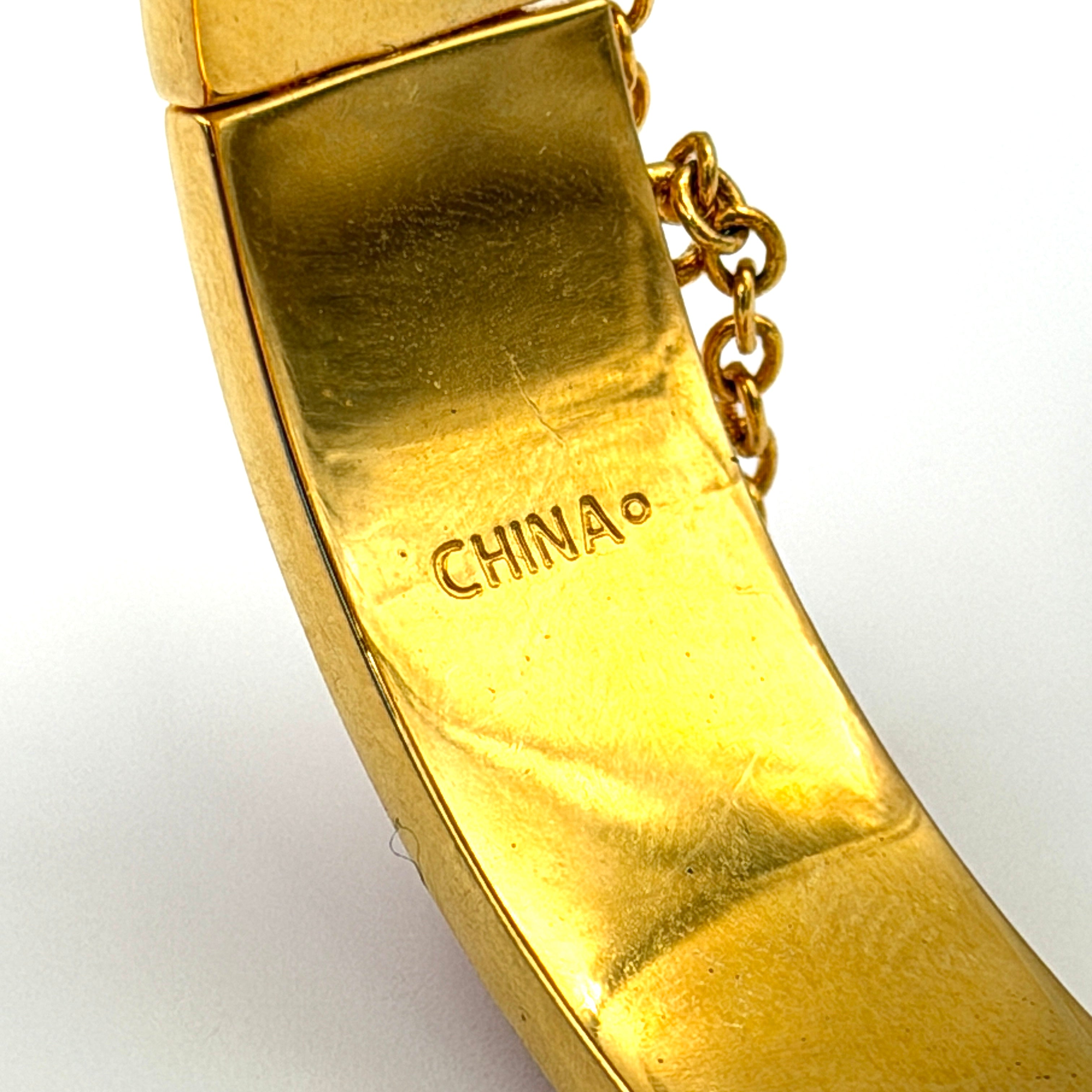 Coach Signature C Bangle Bracelet in gold-tone metal with red enamel, featuring the signature C motif and safety chain.