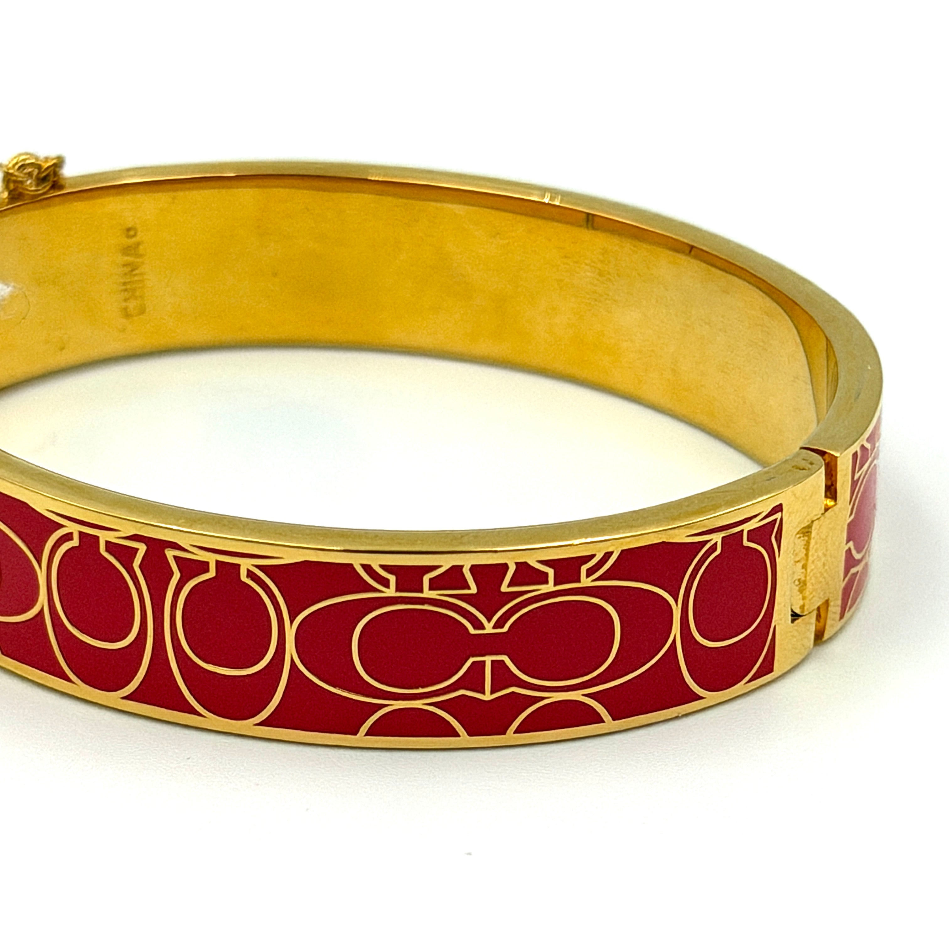 Coach Signature C Bangle Bracelet in gold-tone metal with red enamel, featuring the signature C motif and safety chain.