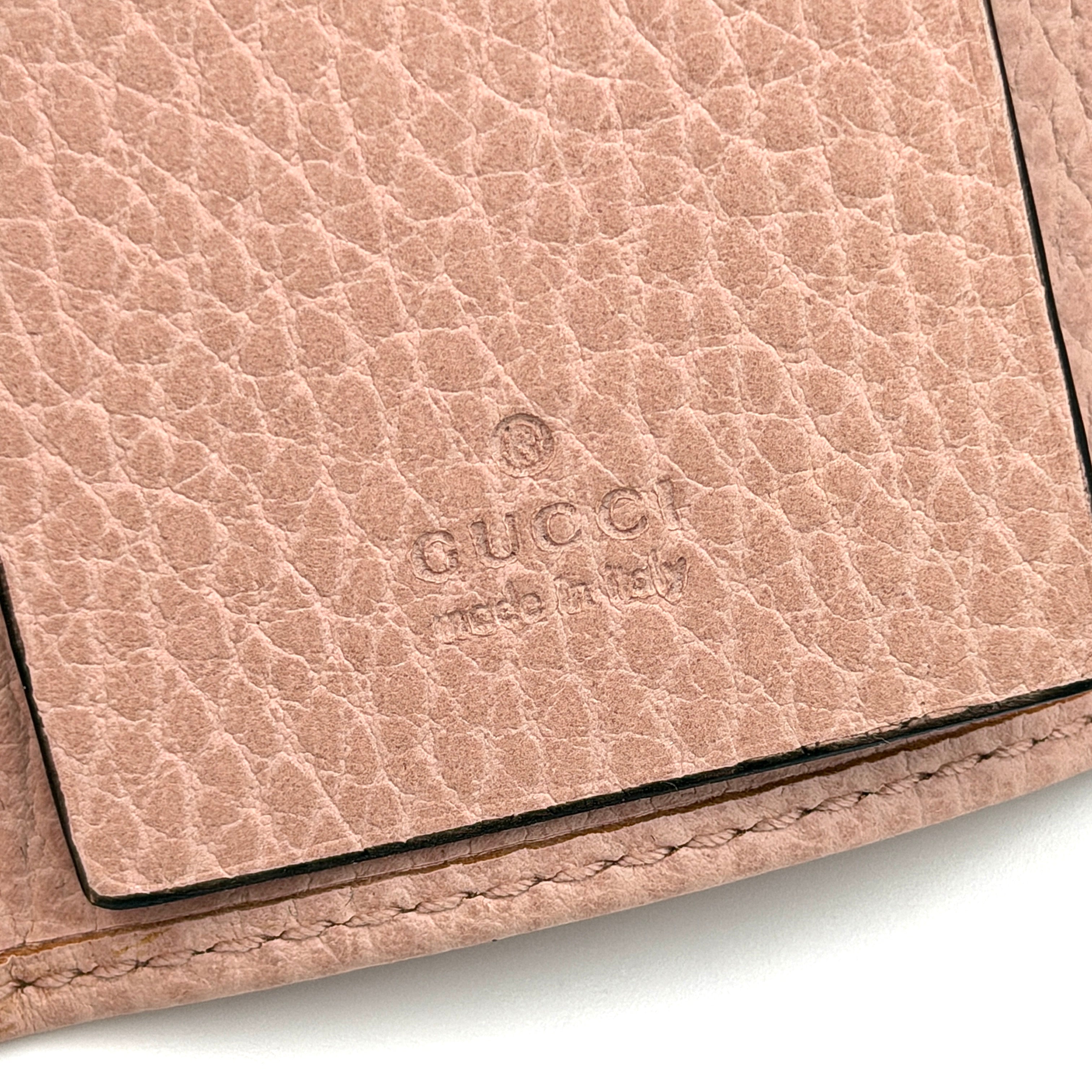 Gucci GG Marmont pink leather key case with gold GG emblem and grained texture, presented in a structured trifold shape.