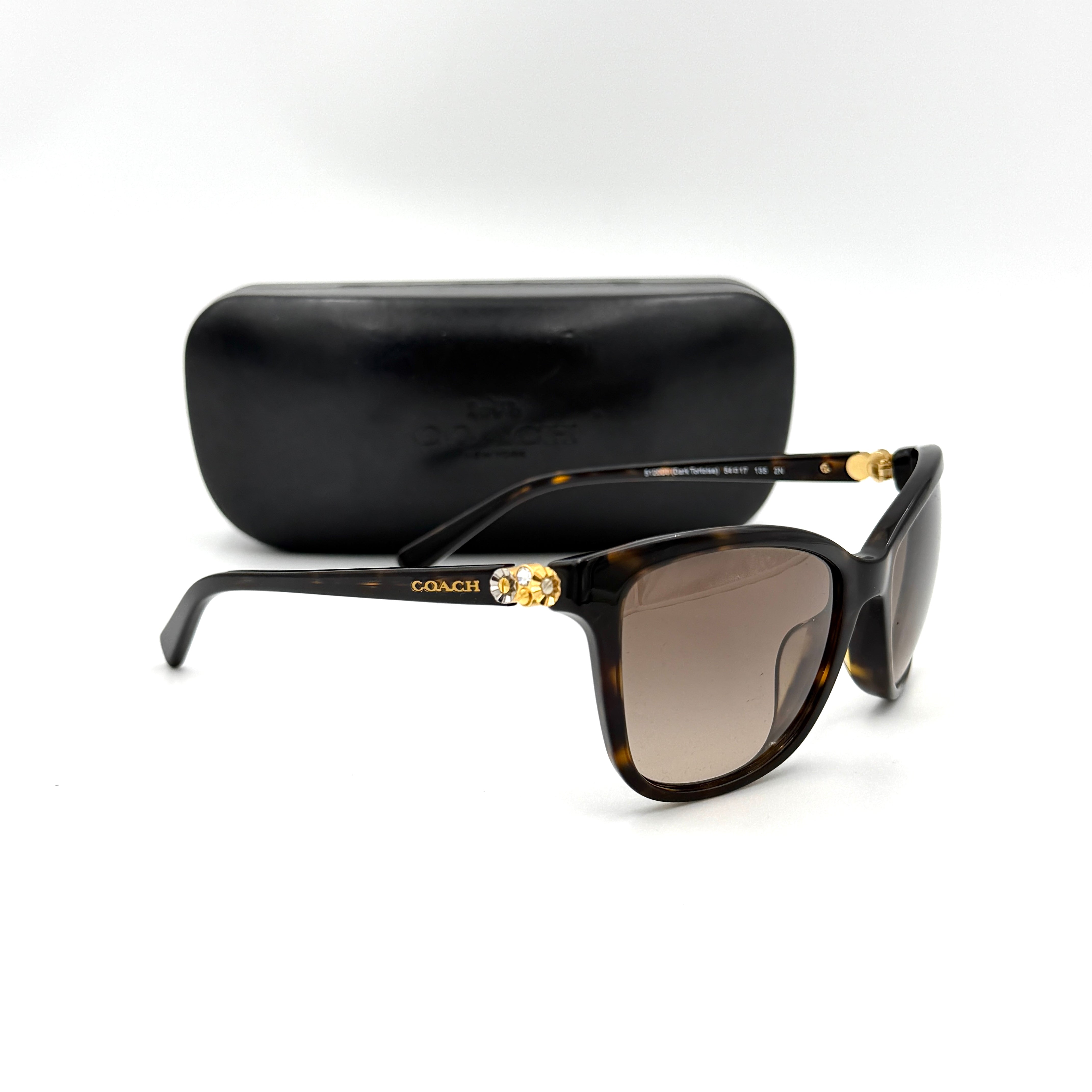 Coach HC8187BF sunglasses in dark tortoise acetate with gold floral and crystal temple detailing, shown in a three-quarter profile.