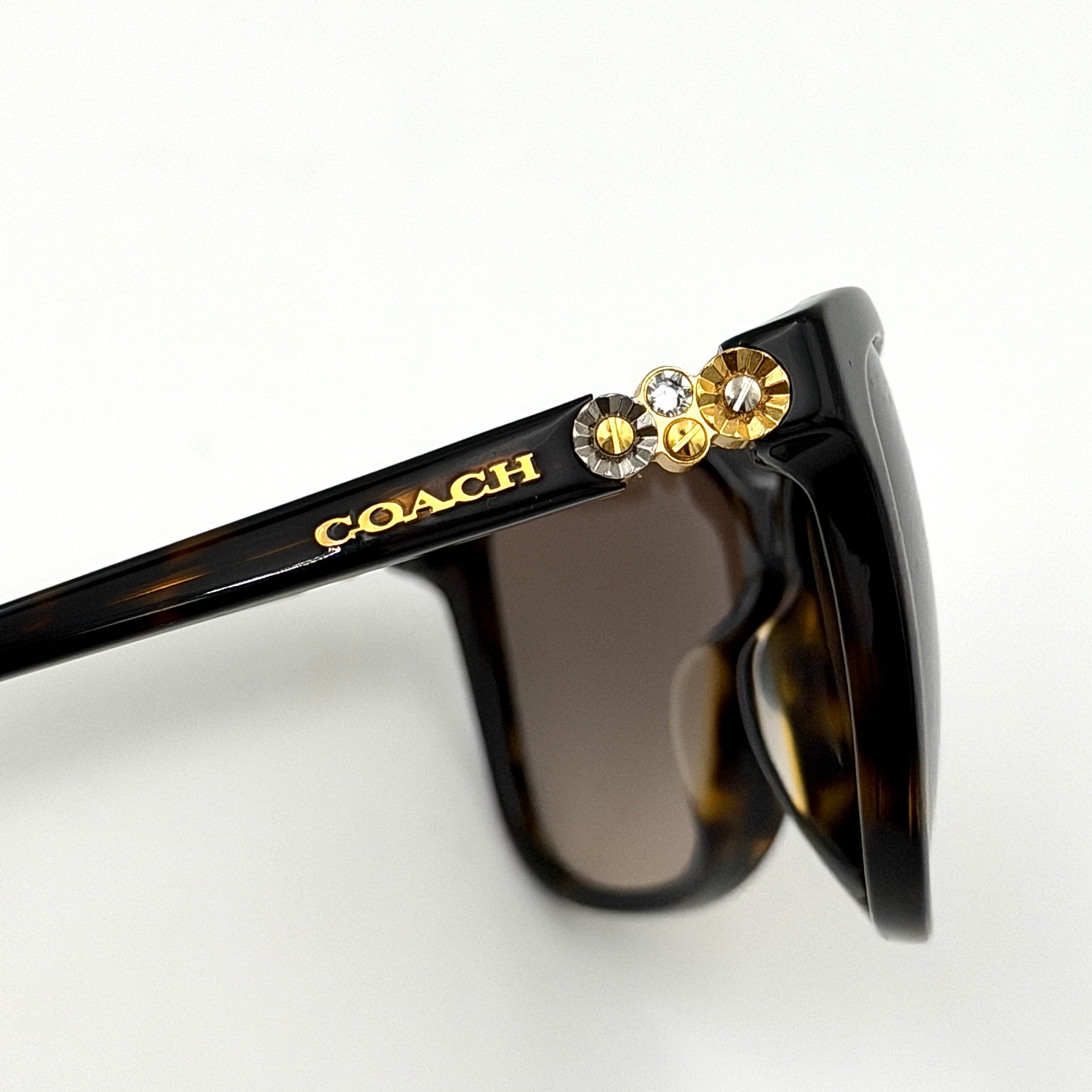 Coach HC8187BF sunglasses in dark tortoise acetate with gold floral and crystal temple detailing, shown in a three-quarter profile.