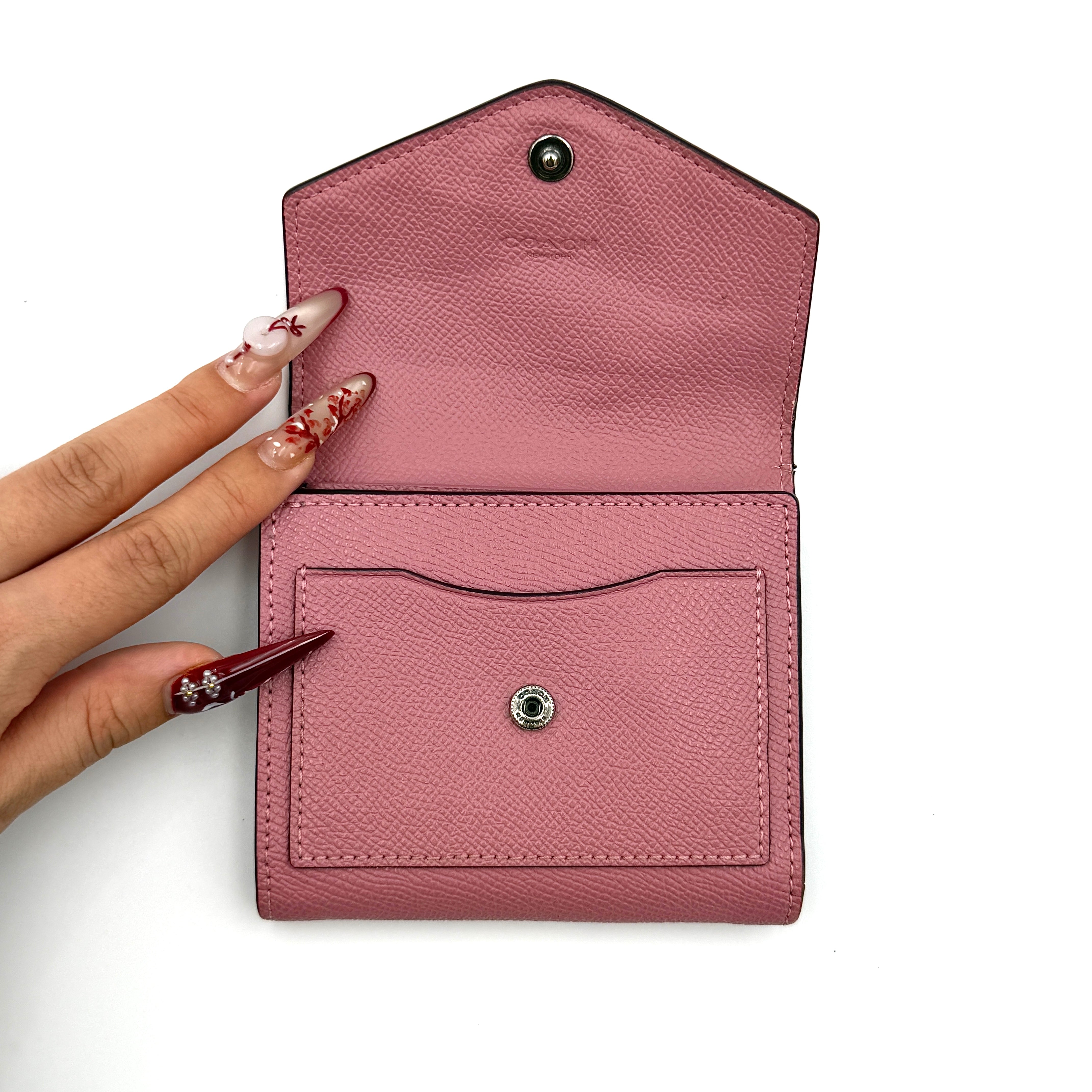 Coach Envelope Small Wallet in dusky pink grained leather with silver hardware and an angular flap closure.