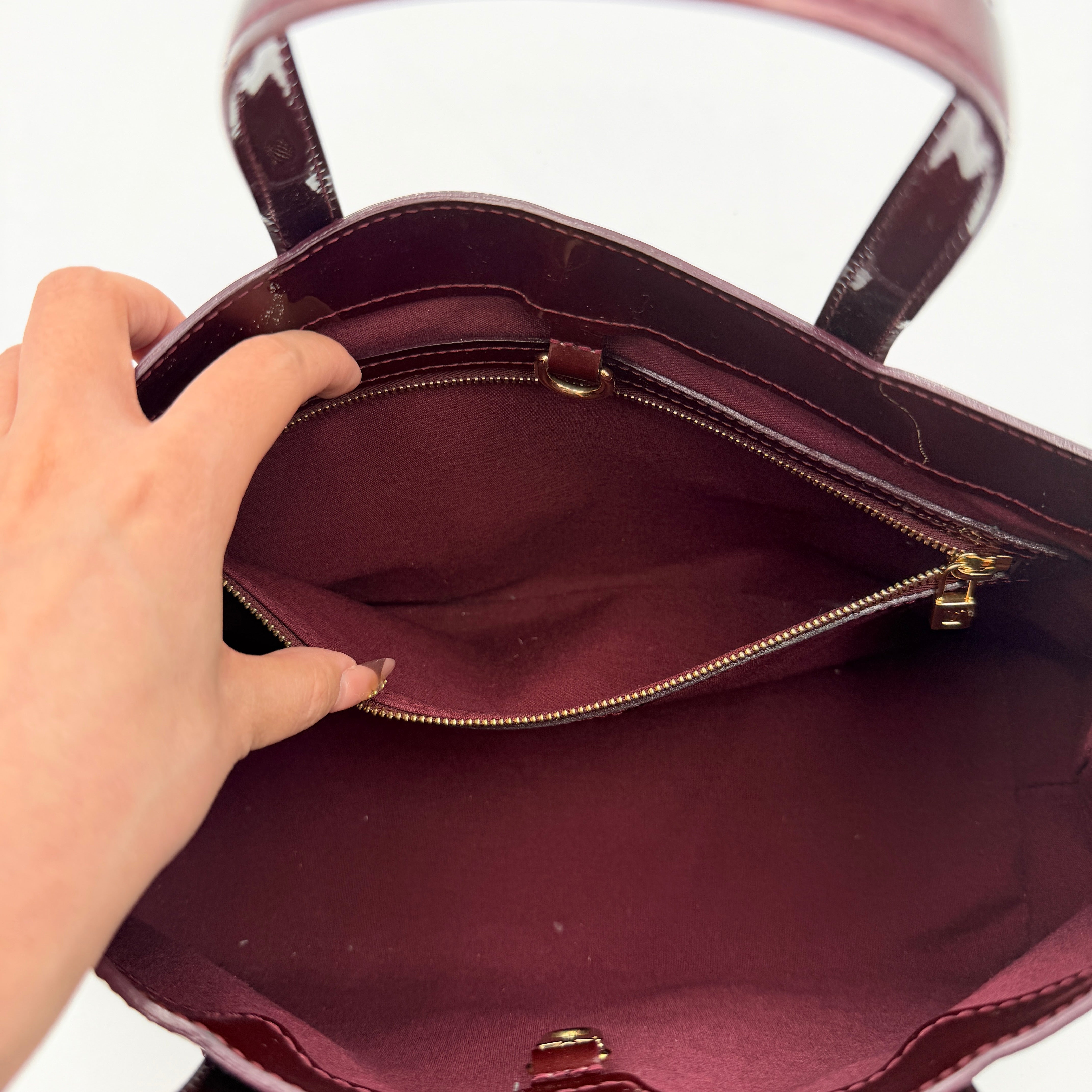 Louis Vuitton Wilshire PM Monogram Vernis bag in glossy deep red with gold nameplate and embossed monogram, displayed against a clean background.
