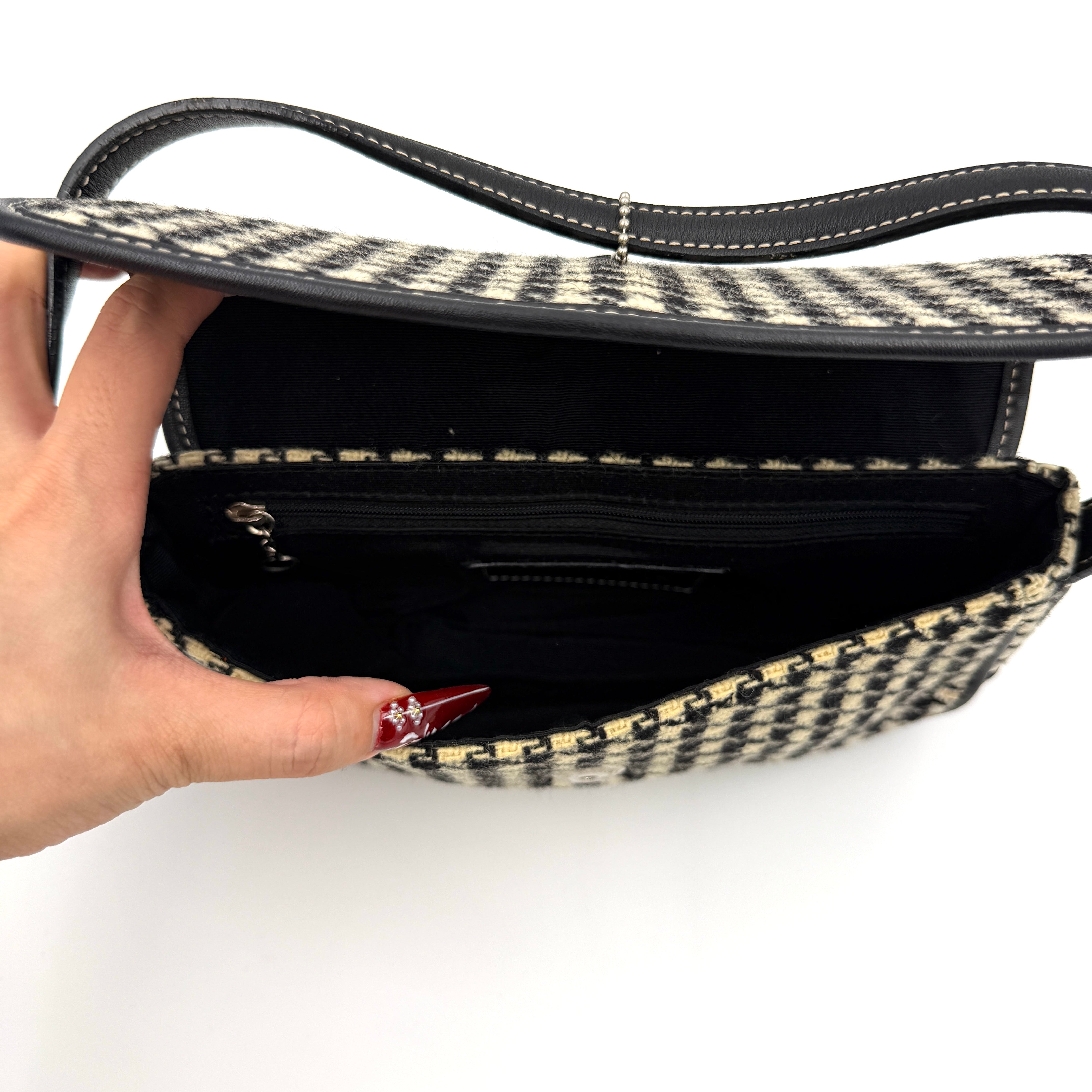 Coach Y2K shoulder bag with a bold black and cream houndstooth pattern and sleek leather trim.