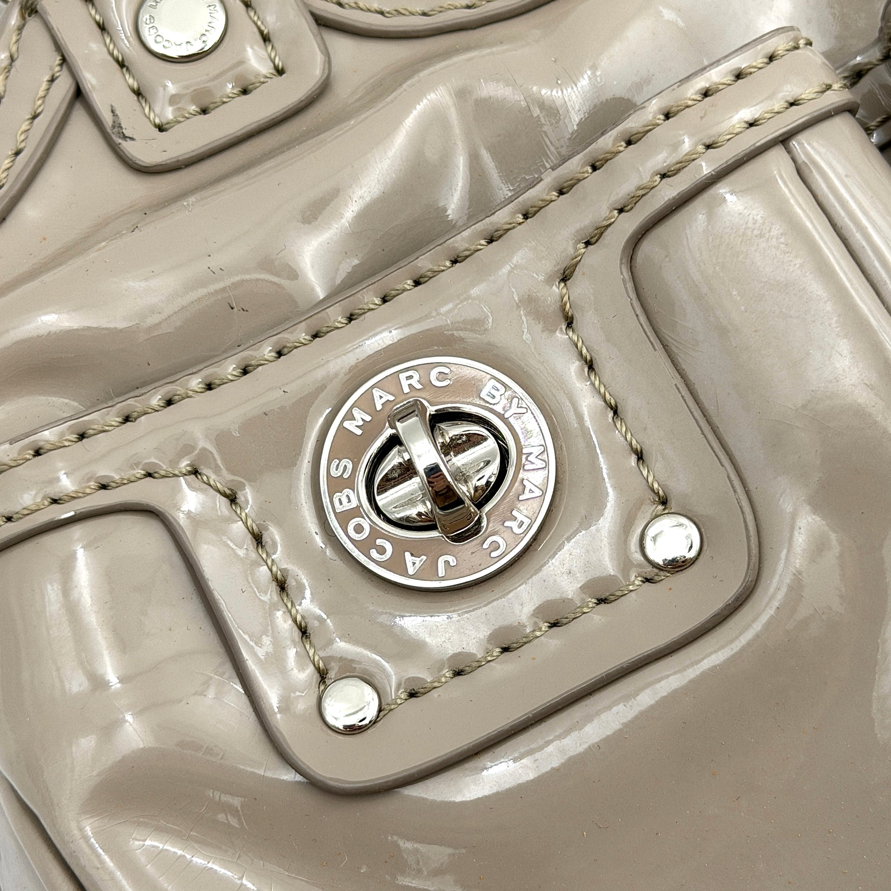 Marc Jacobs grey patent leather shoulder bag with double front turnlock pockets and structured dual handles.
