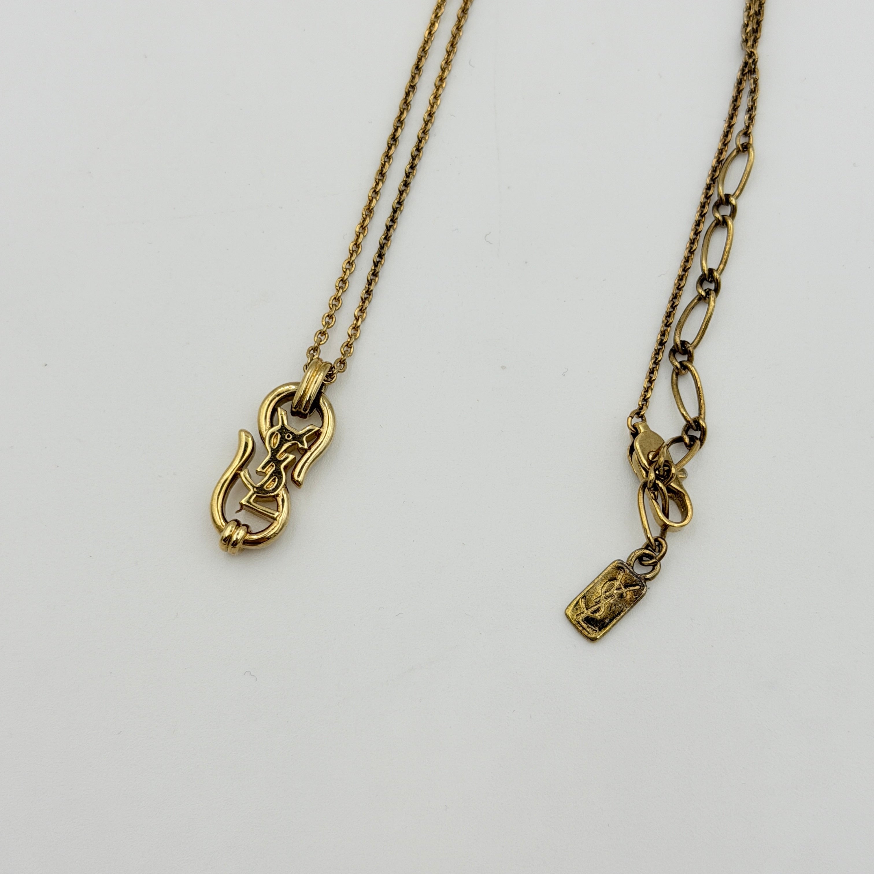 Saint Laurent Cassandre Logo Necklace in gold metal with signature YSL pendant displayed on a necklace stand.