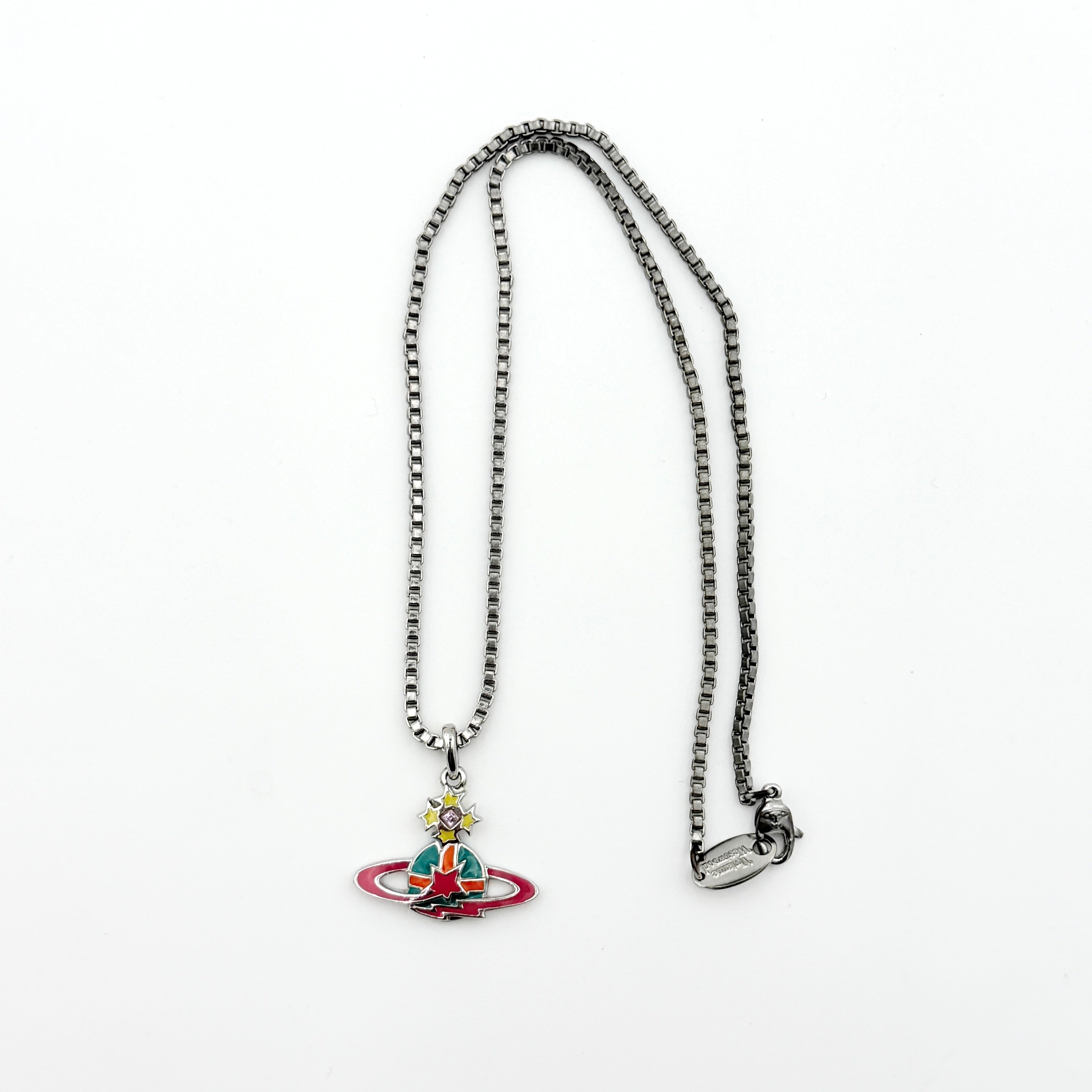 Vivienne Westwood Shooting Star Orb Necklace in silver with vibrant multi-coloured enamel details displayed on a cream jewellery stand.