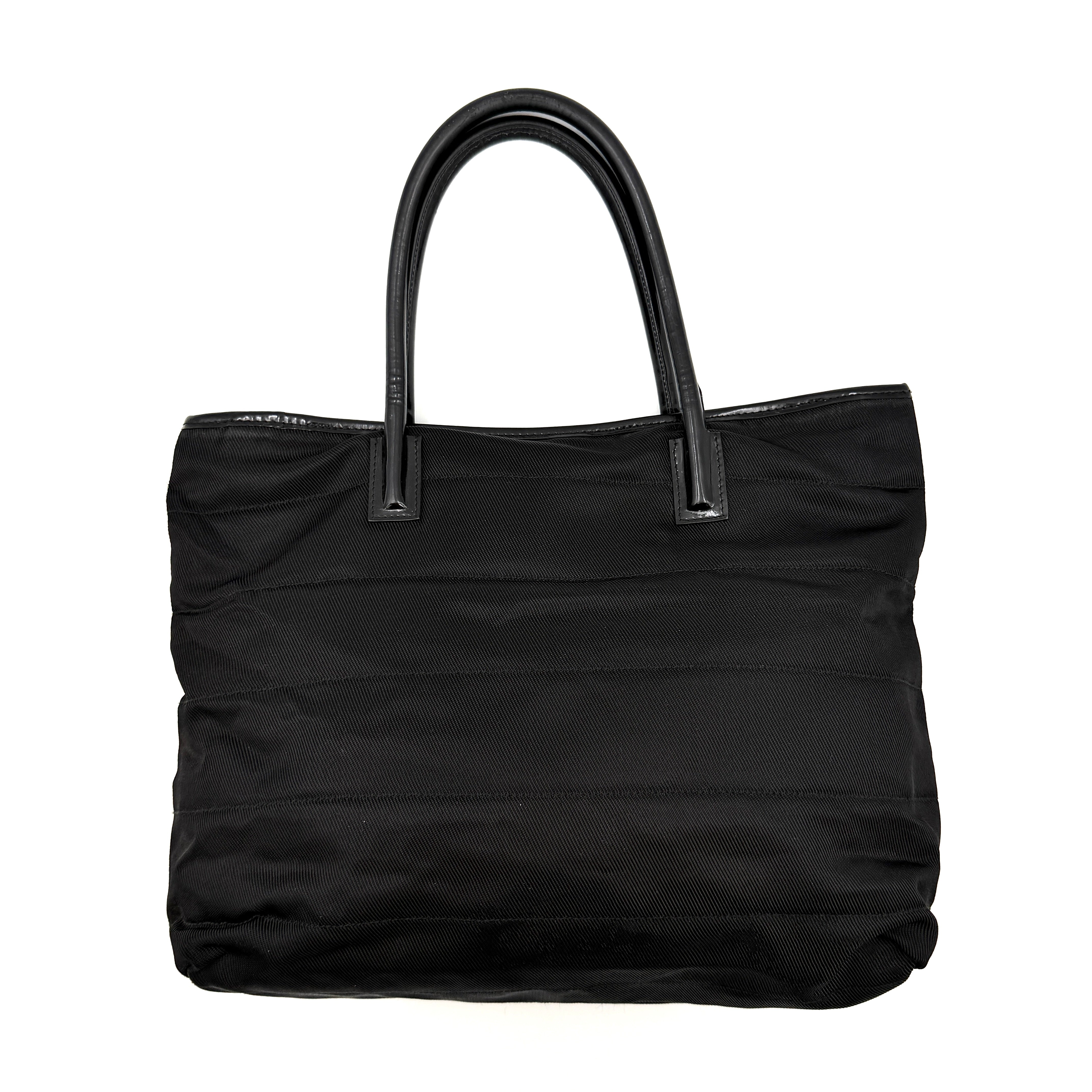 A classic black Gucci nylon tote bag with leather handles and gold-tone hardware displayed upright against a clean background.