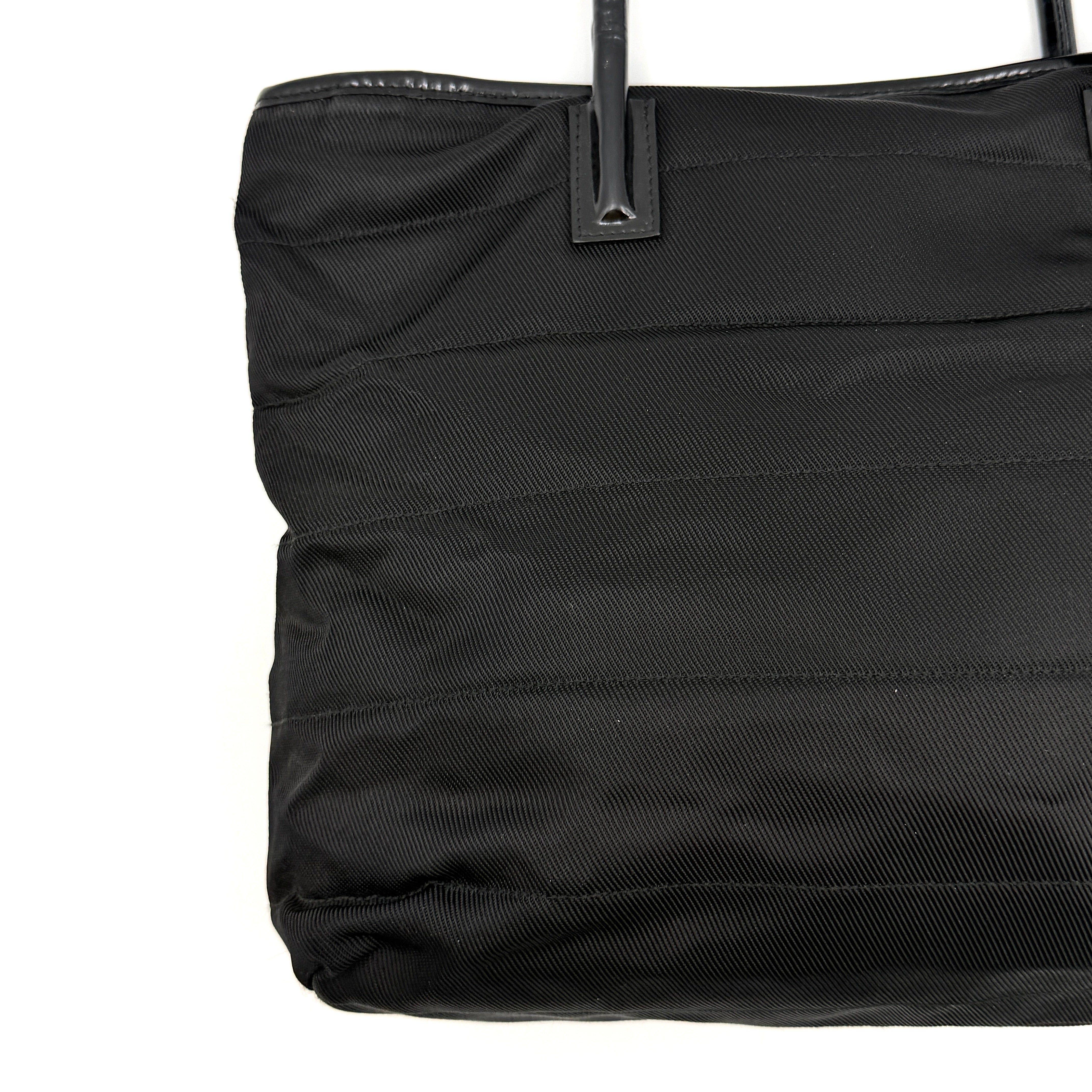 A classic black Gucci nylon tote bag with leather handles and gold-tone hardware displayed upright against a clean background.