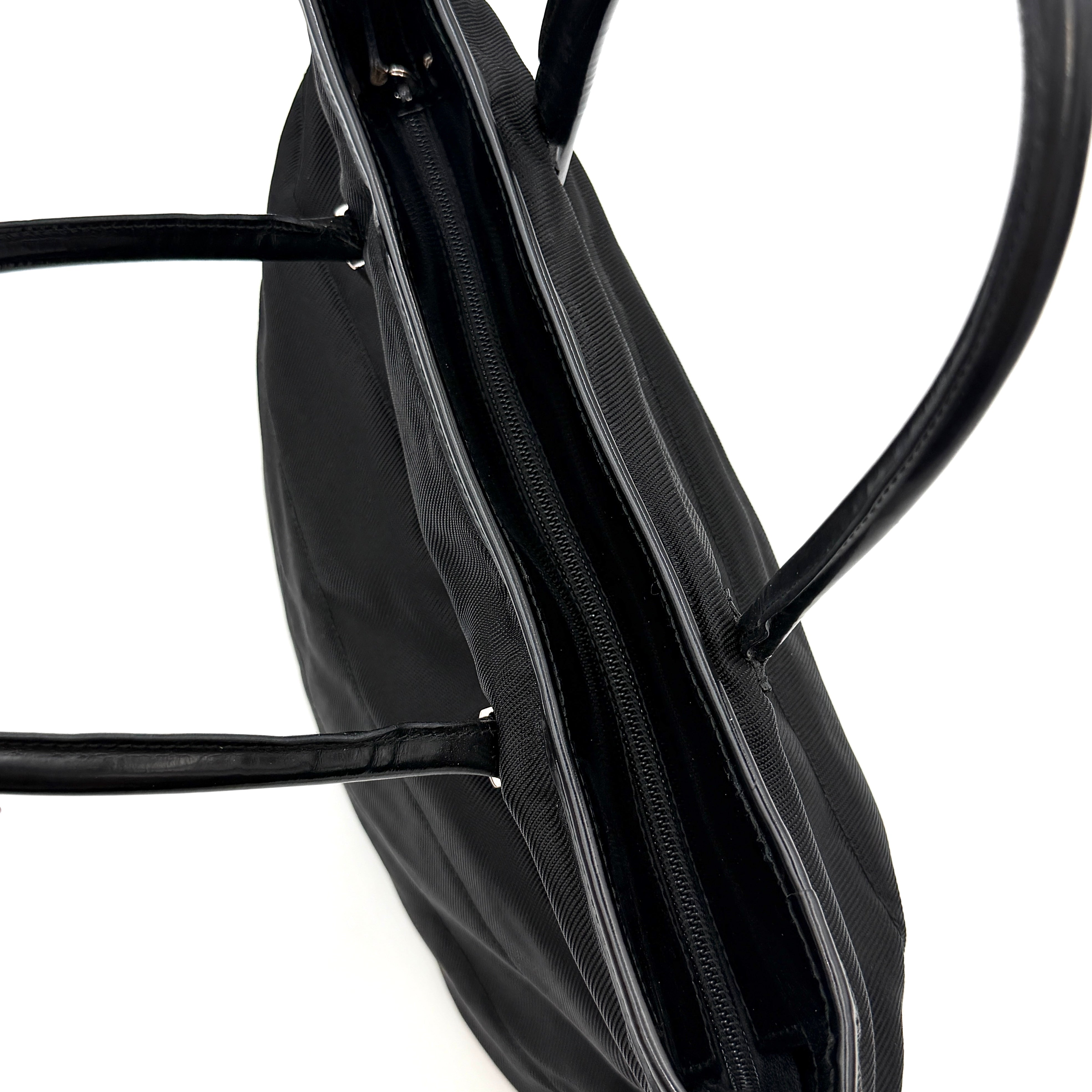 A classic black Gucci nylon tote bag with leather handles and gold-tone hardware displayed upright against a clean background.