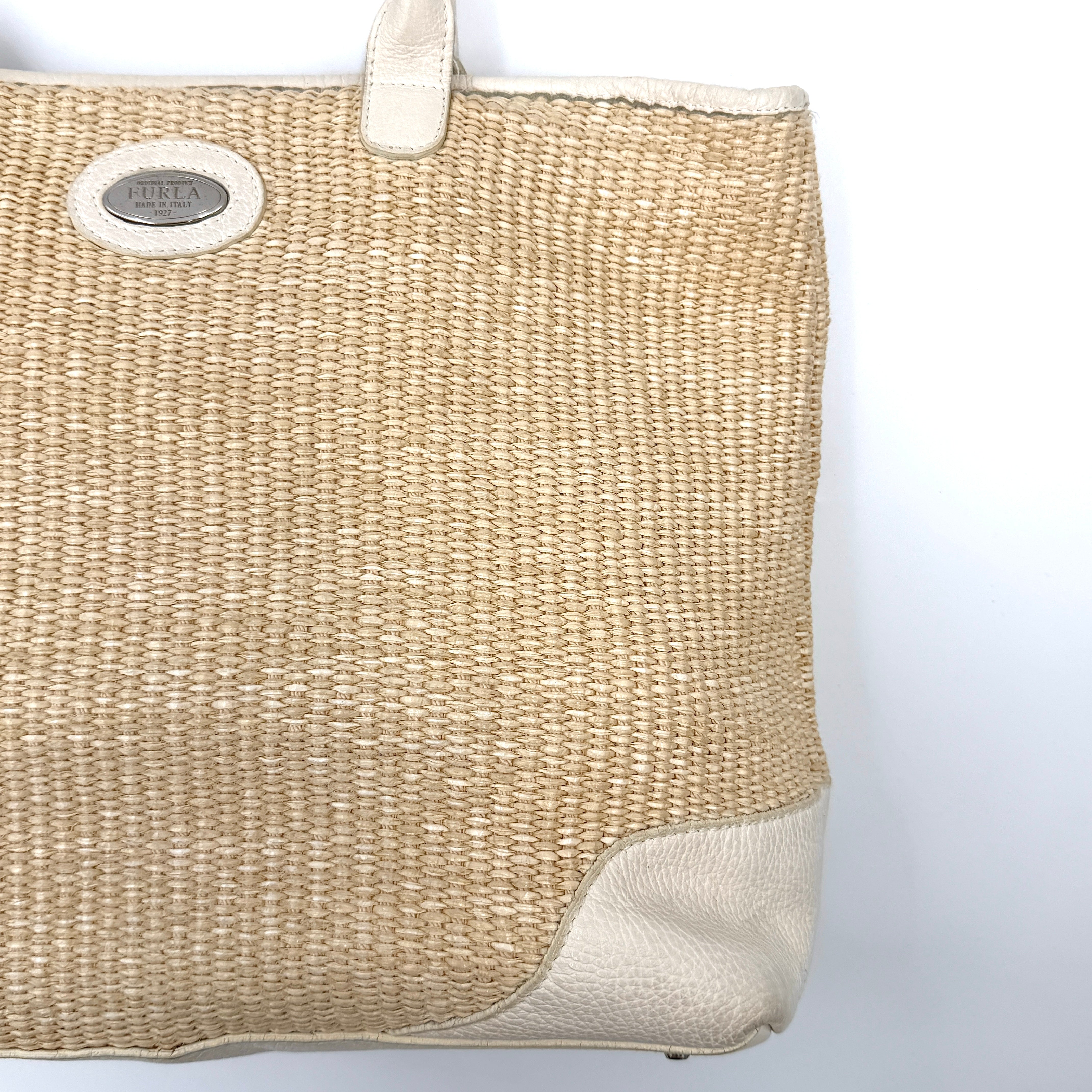 Furla beige woven straw tote bag with off-white leather handles and corners, featuring a silver oval logo plaque.