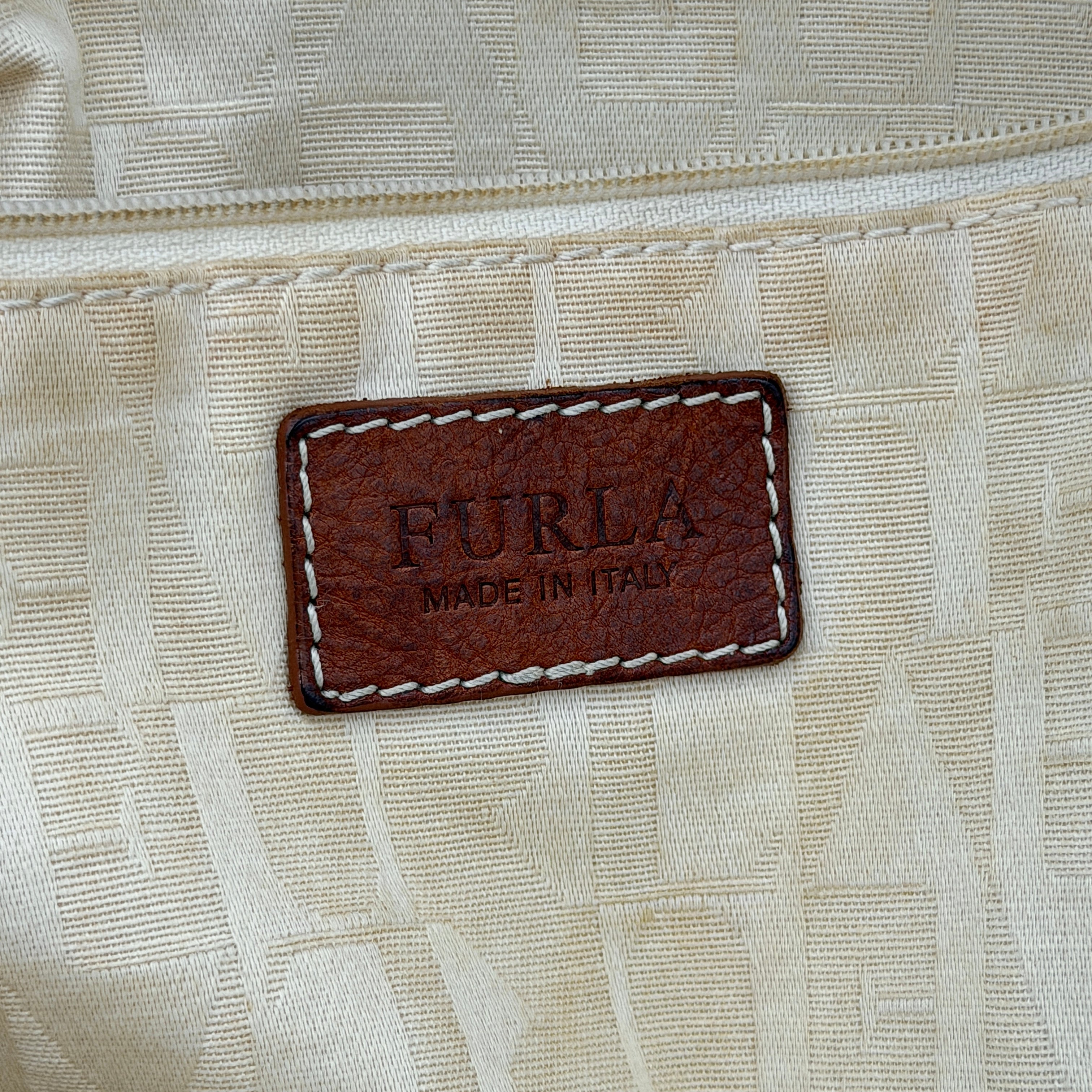 Furla beige woven straw tote bag with off-white leather handles and corners, featuring a silver oval logo plaque.