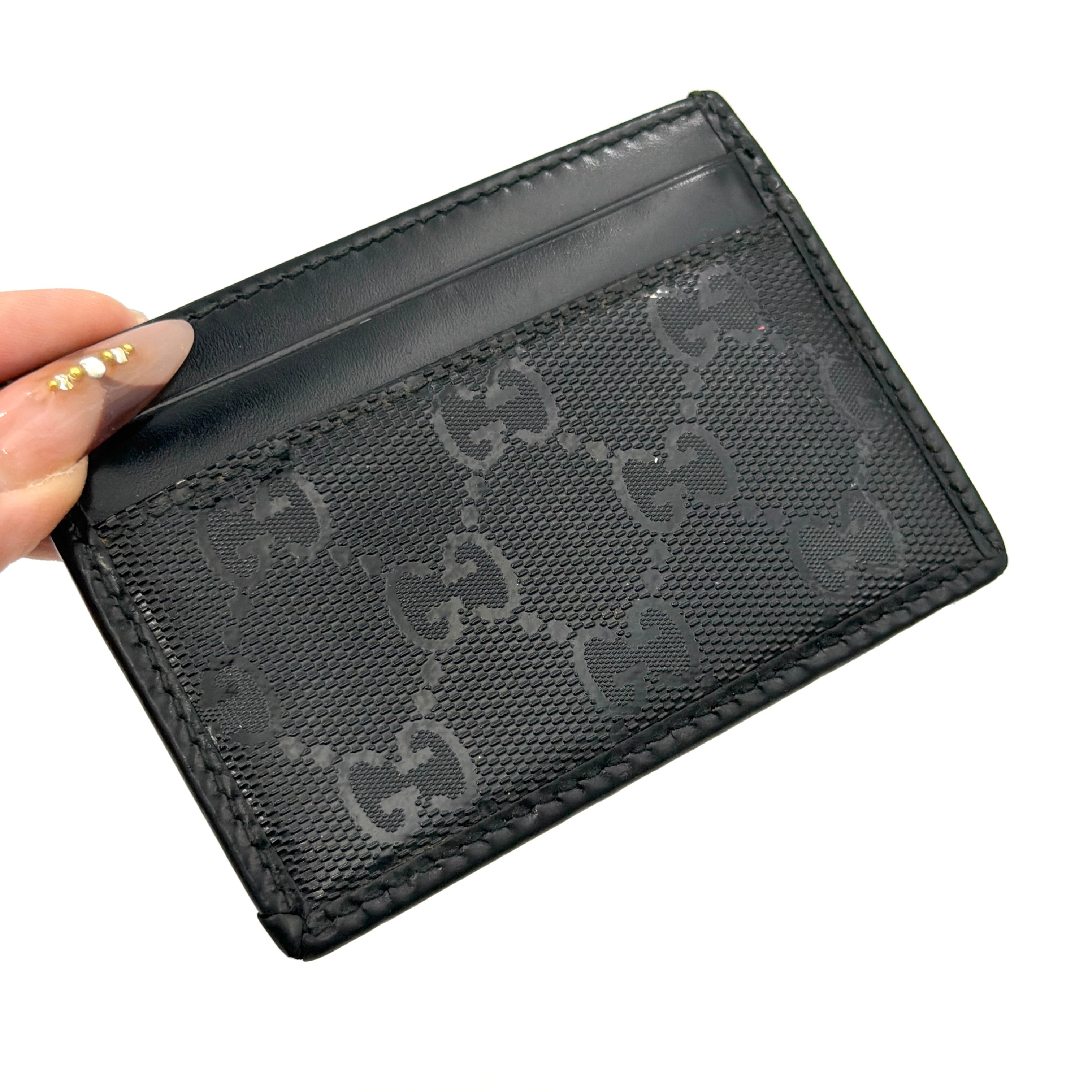 Gucci GG Monogram card holder in black canvas and leather, featuring tonal logo pattern and four exterior card slots.