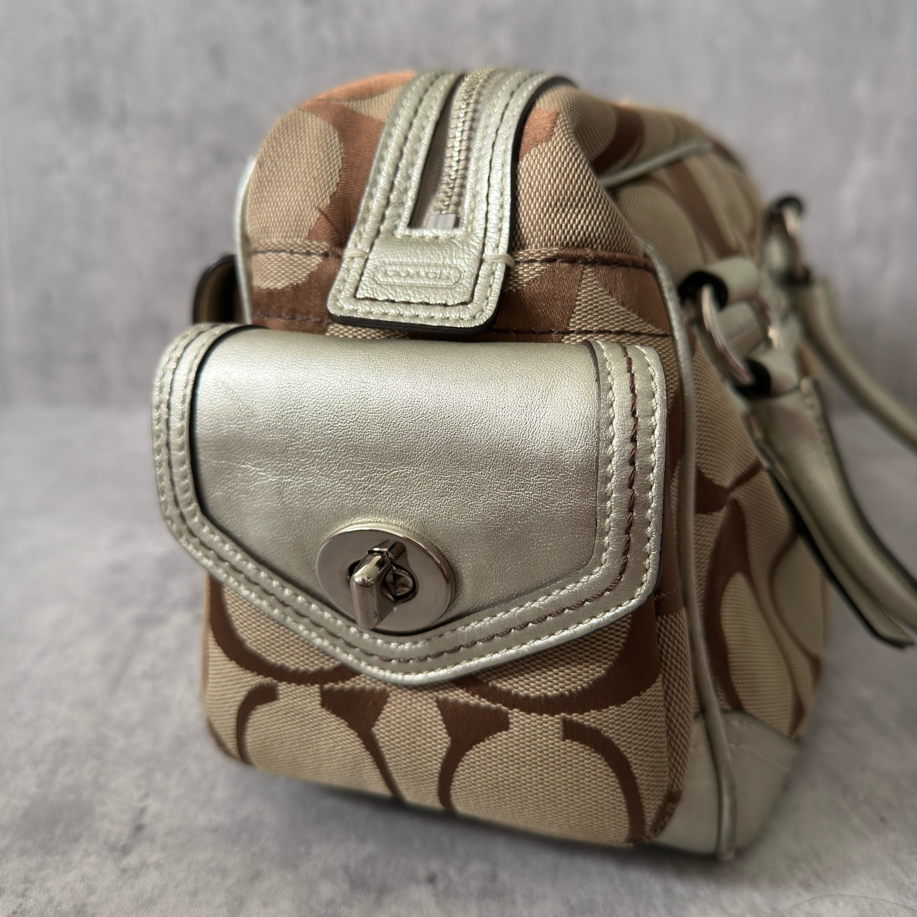 Coach 2Way Poppy Signature Bag in beige monogram canvas with silver leather trim, featuring double handles, turn-lock front pockets, and a spacious interior.