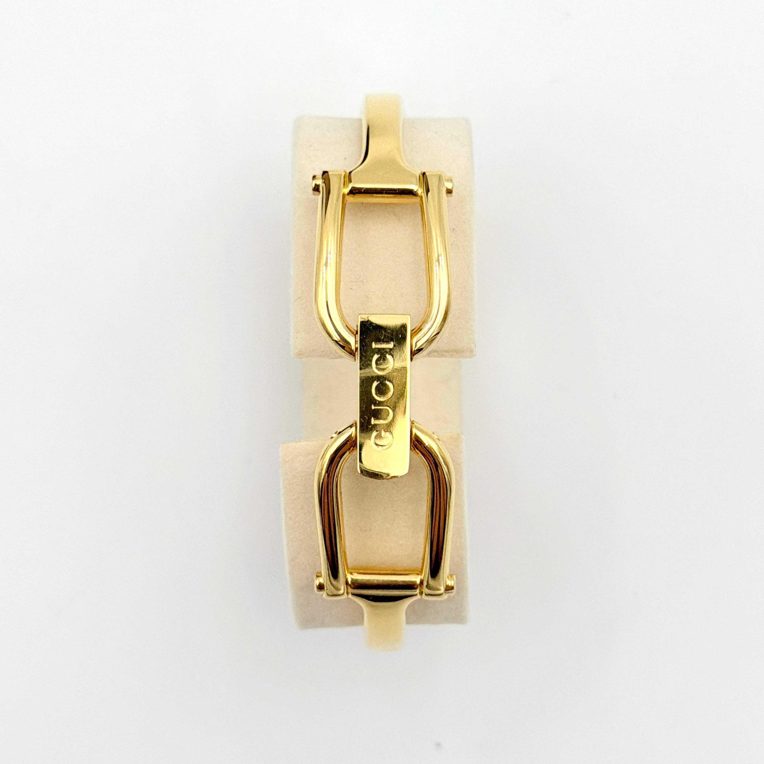 Gucci 1500L gold-tone quartz watch with white rectangular dial, displayed in box with warranty card.