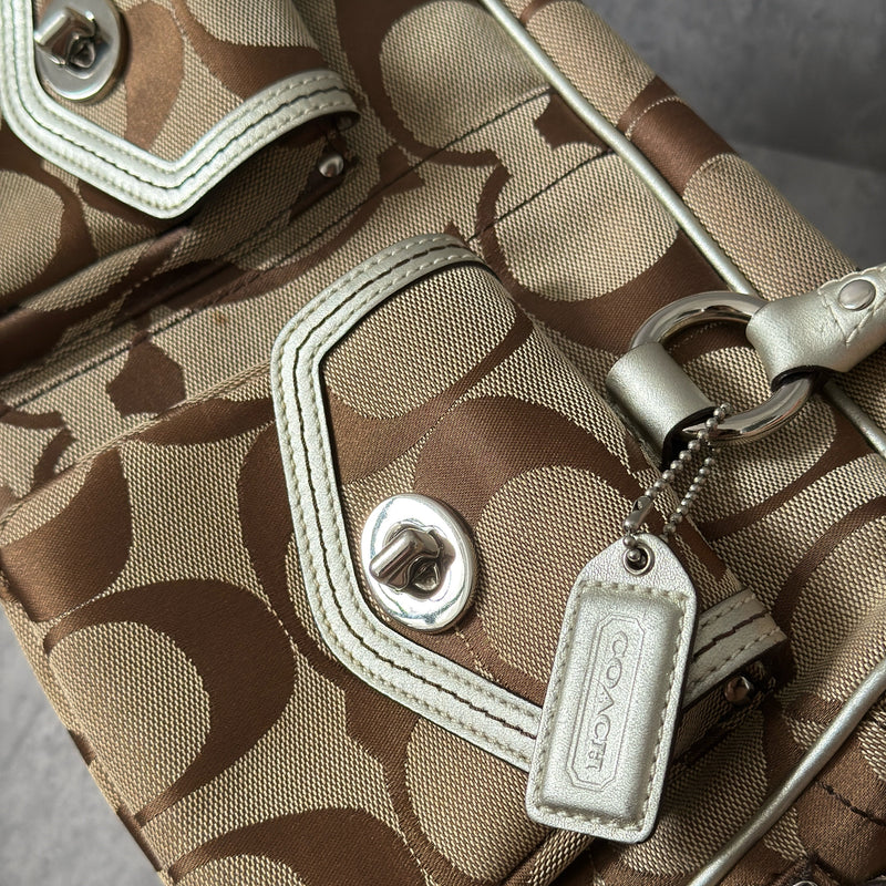 Coach 2Way Poppy Signature Bag in beige monogram canvas with silver leather trim, featuring double handles, turn-lock front pockets, and a spacious interior.