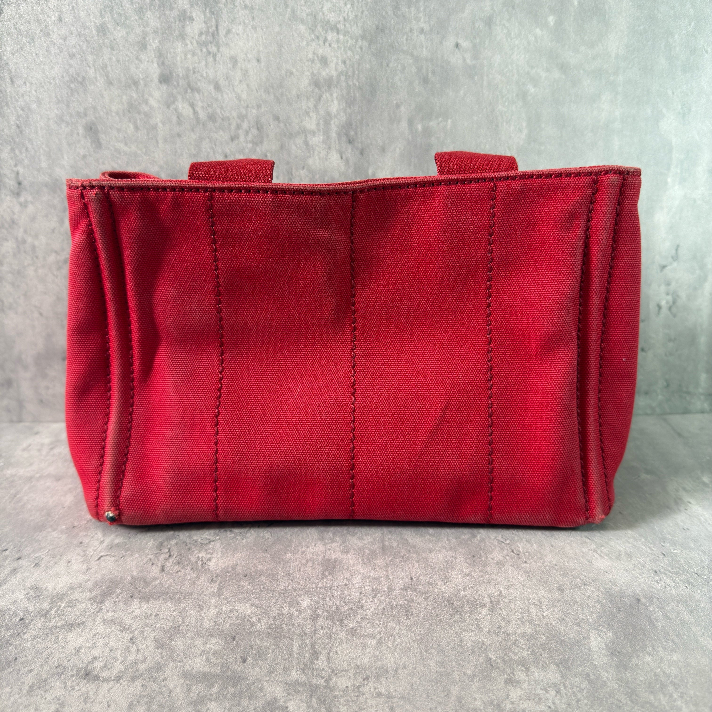 Prada Canapa Tote Bag in red canvas with black logo embroidery, featuring a structured silhouette and dual top handles for effortless style.
