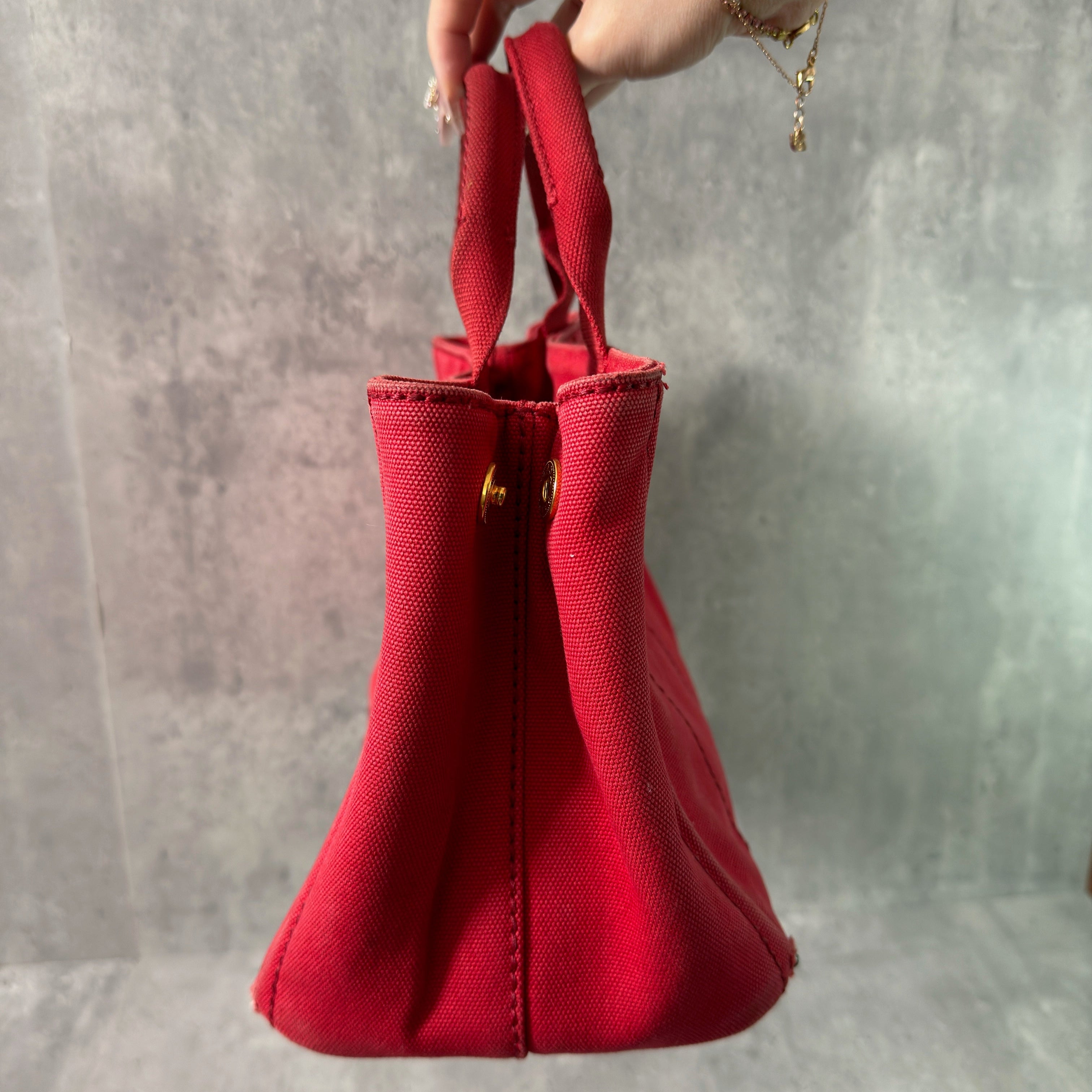 Prada Canapa Tote Bag in red canvas with black logo embroidery, featuring a structured silhouette and dual top handles for effortless style.