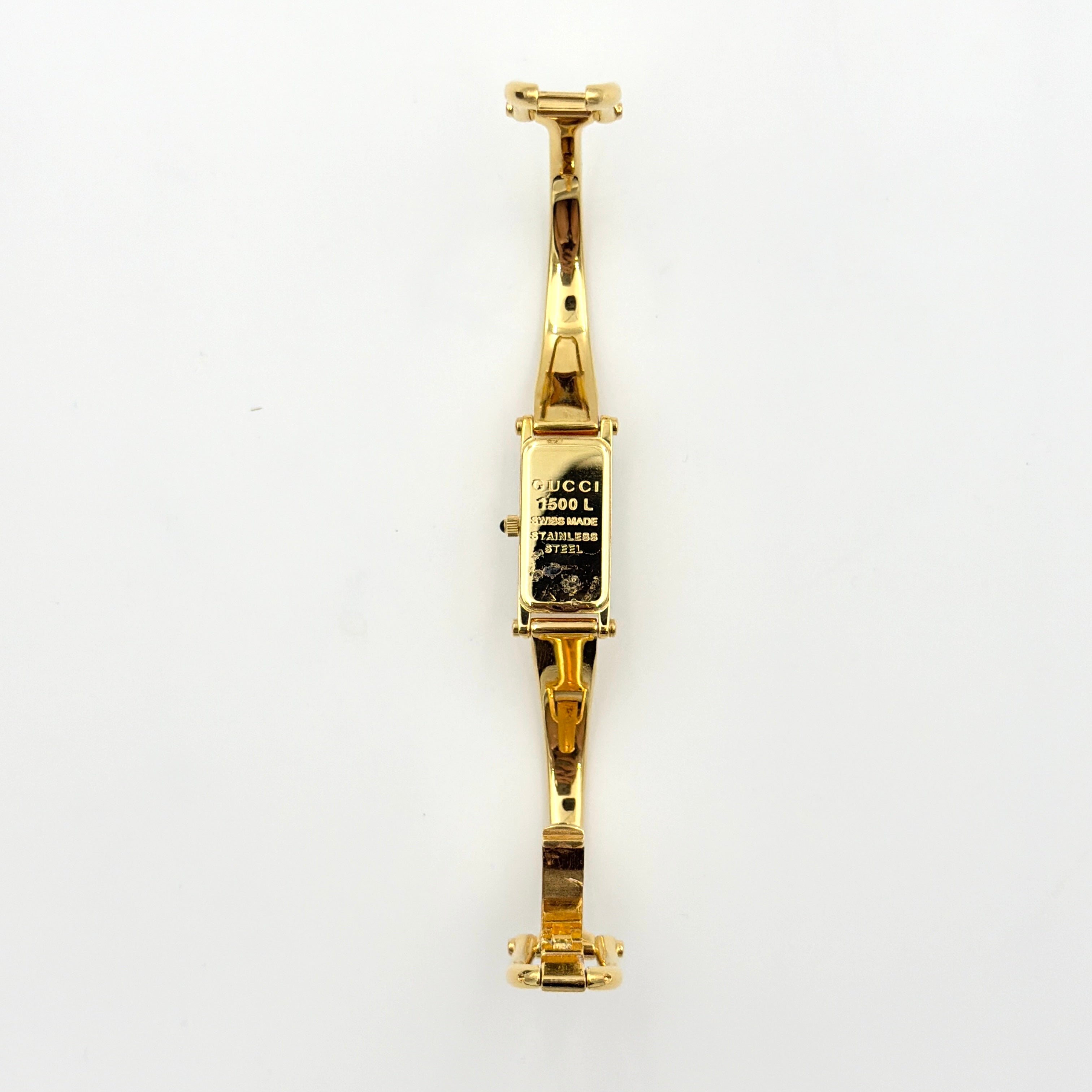 Gucci 1500L gold-tone quartz watch with white rectangular dial, displayed in box with warranty card.