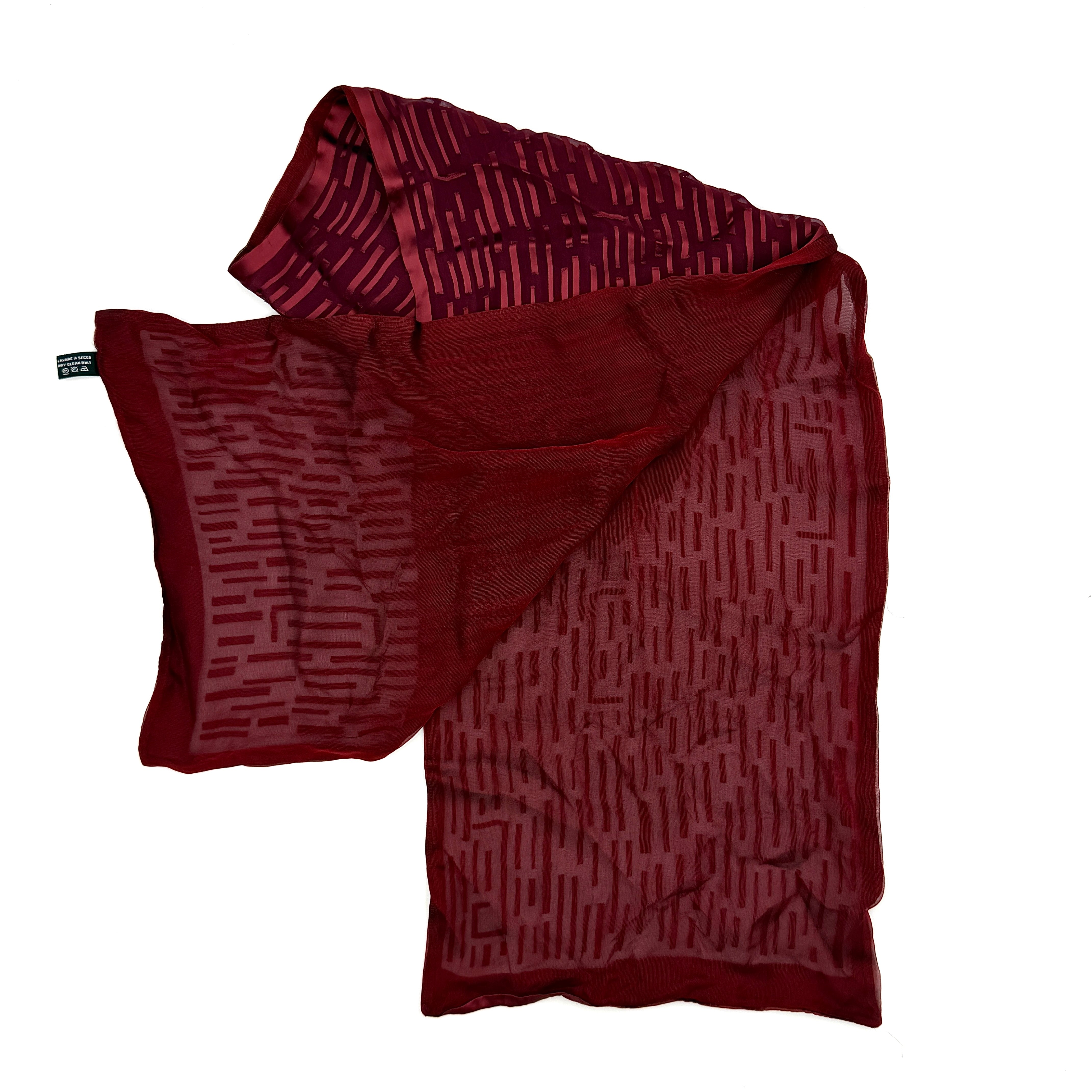 A maroon Gucci silk scarf with a tonal geometric jacquard pattern and a lustrous silk border, elegantly displayed to highlight its texture.