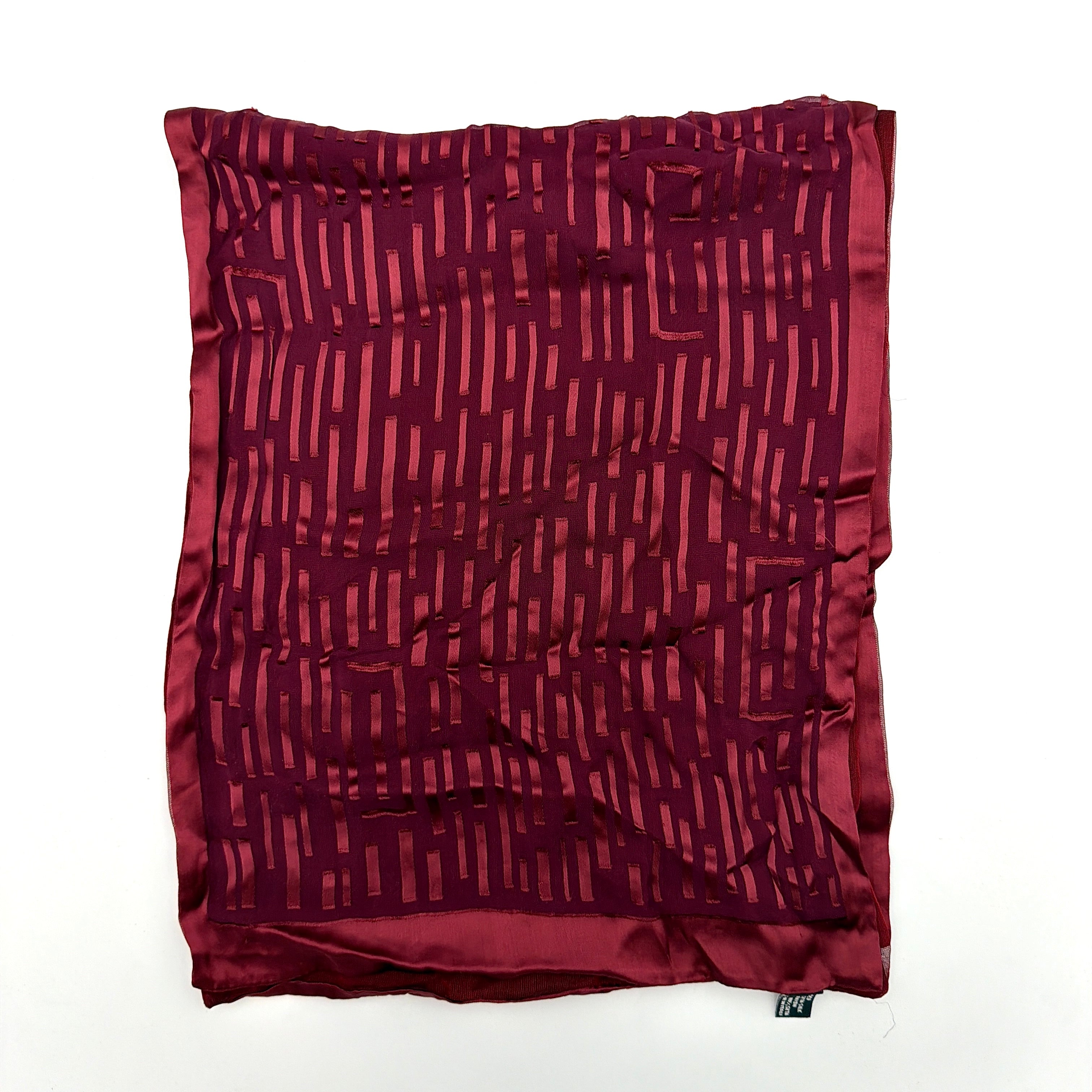 A maroon Gucci silk scarf with a tonal geometric jacquard pattern and a lustrous silk border, elegantly displayed to highlight its texture.