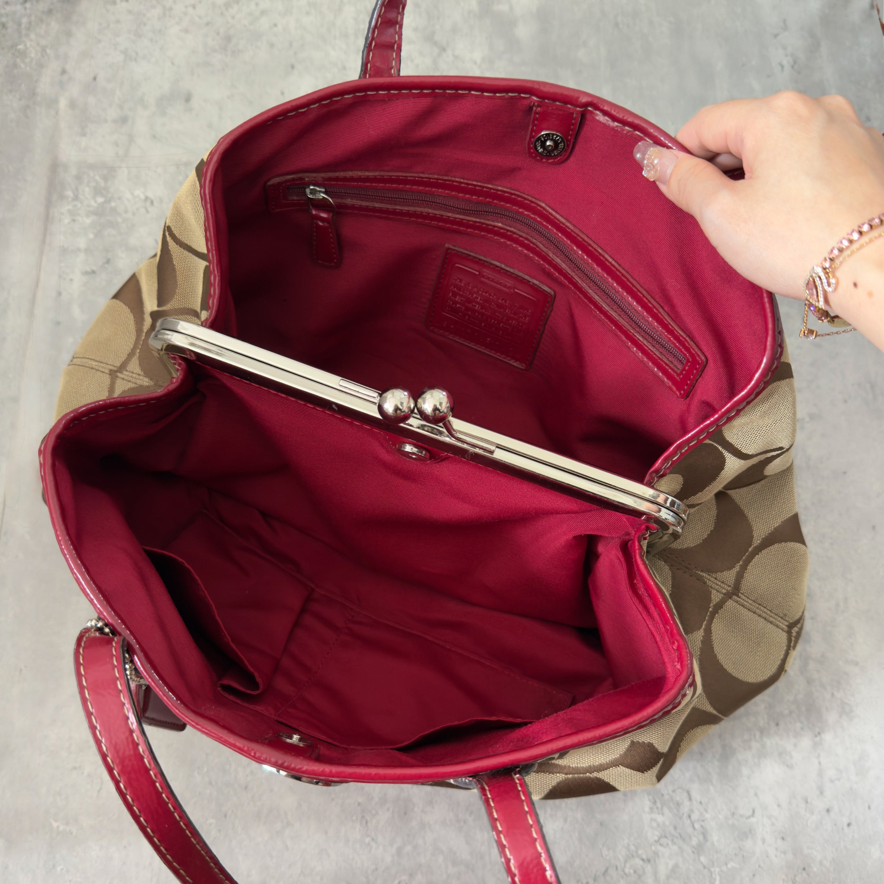 Coach Framed Kiss Lock Carryall Satchel in tan and red stripe with signature monogram canvas, silver-tone hardware, and spacious red fabric-lined interior.