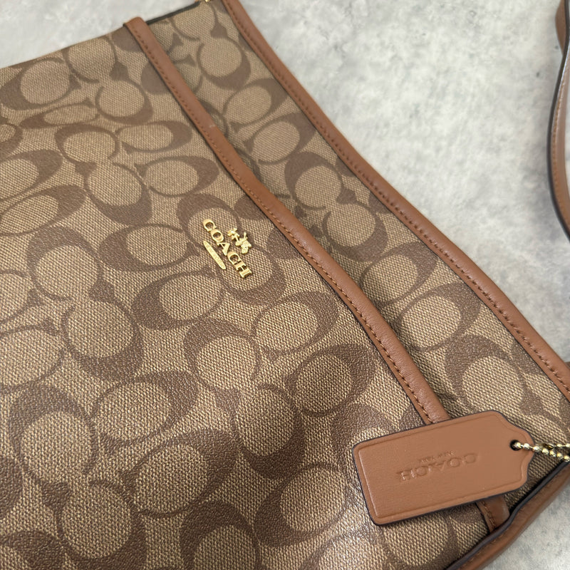 Coach Signature File Crossbody Bag in beige and brown monogram canvas, featuring leather trim, gold-tone hardware, and an adjustable crossbody strap.