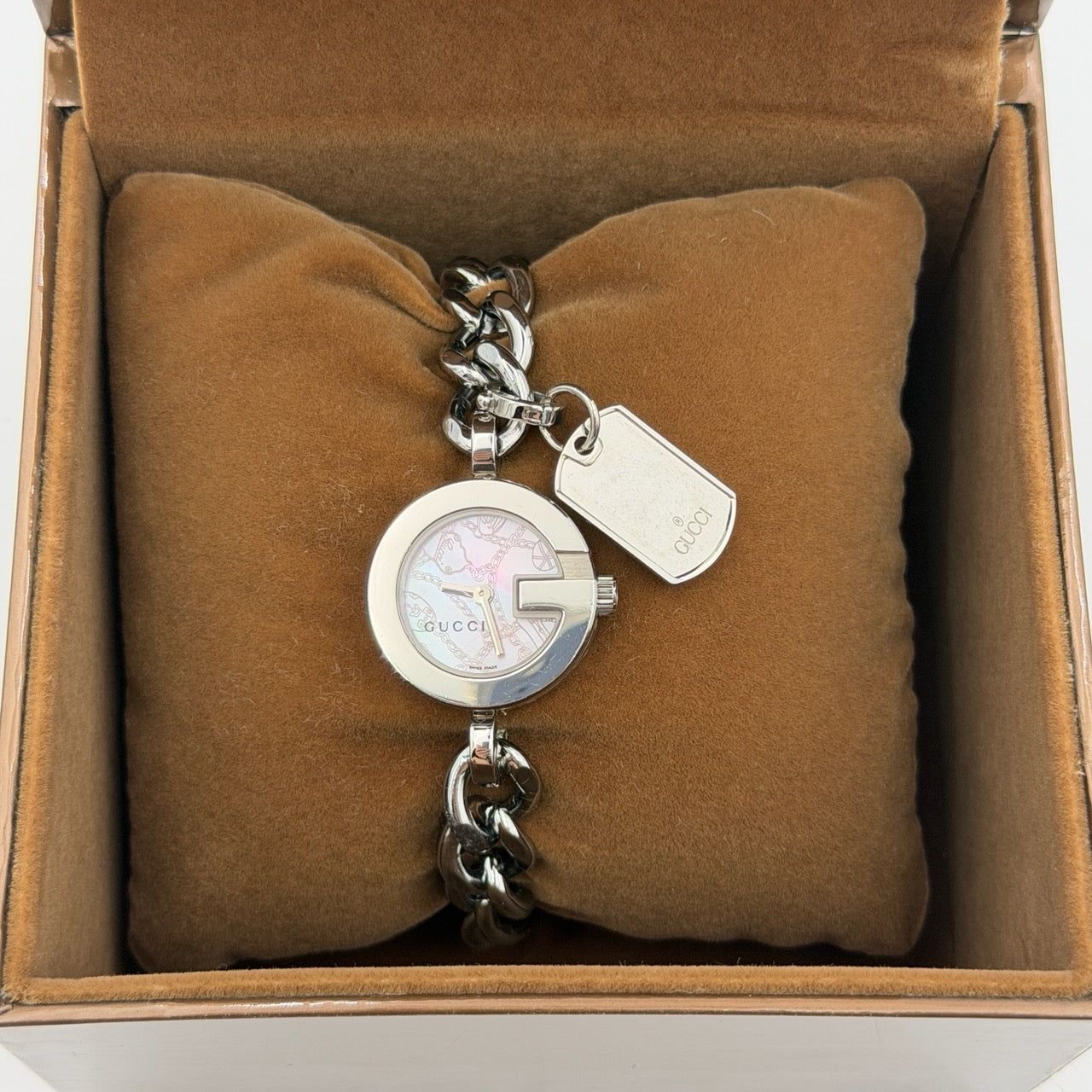 Gucci 107 G Charm Bracelet Watch with silver chunky chain and pink dial, styled on a brown cushion with original Gucci box.