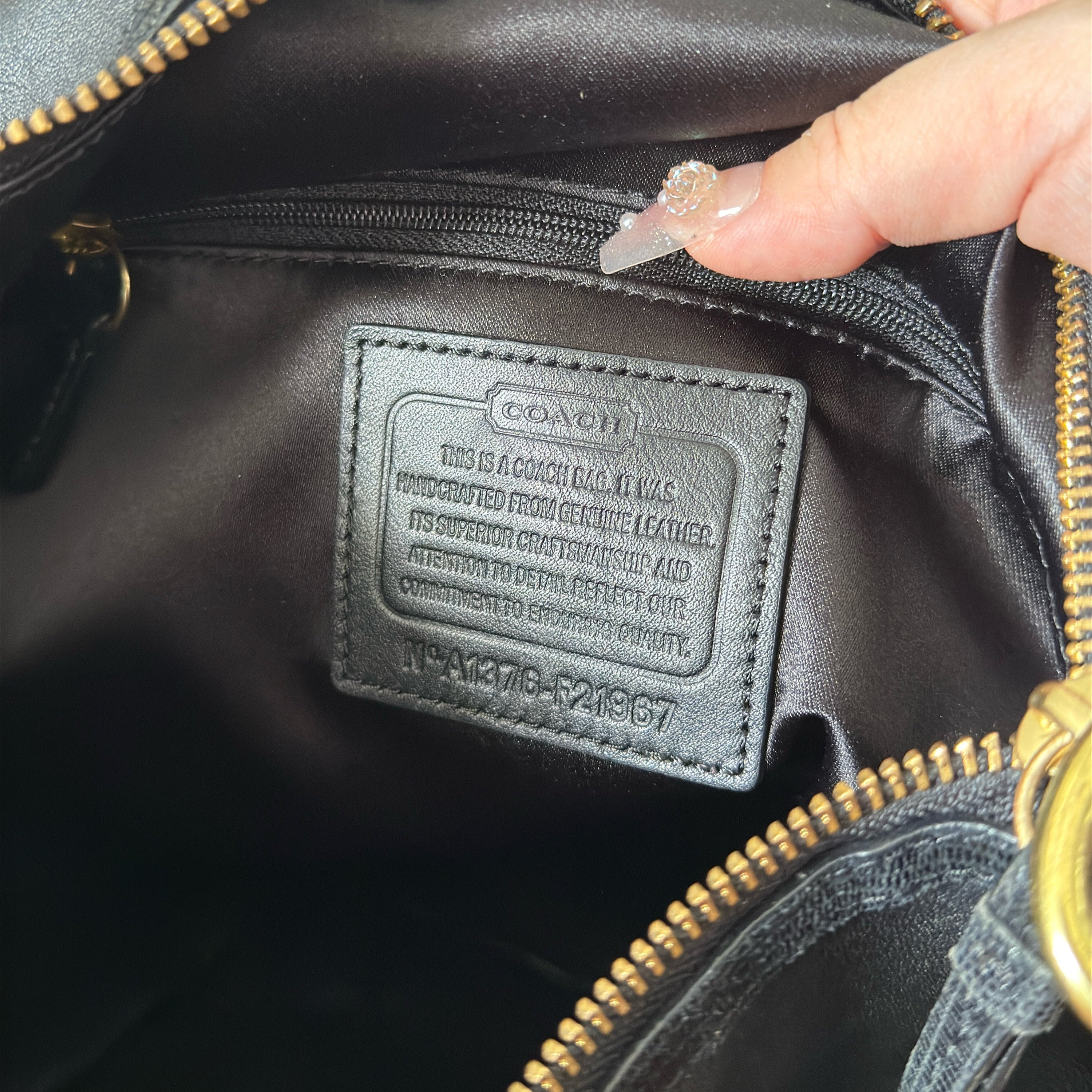 Coach Signature Cursive Logo Shoulder Bag in black leather with gold-tone hardware, featuring a spacious fabric-lined interior and signature Coach charm.