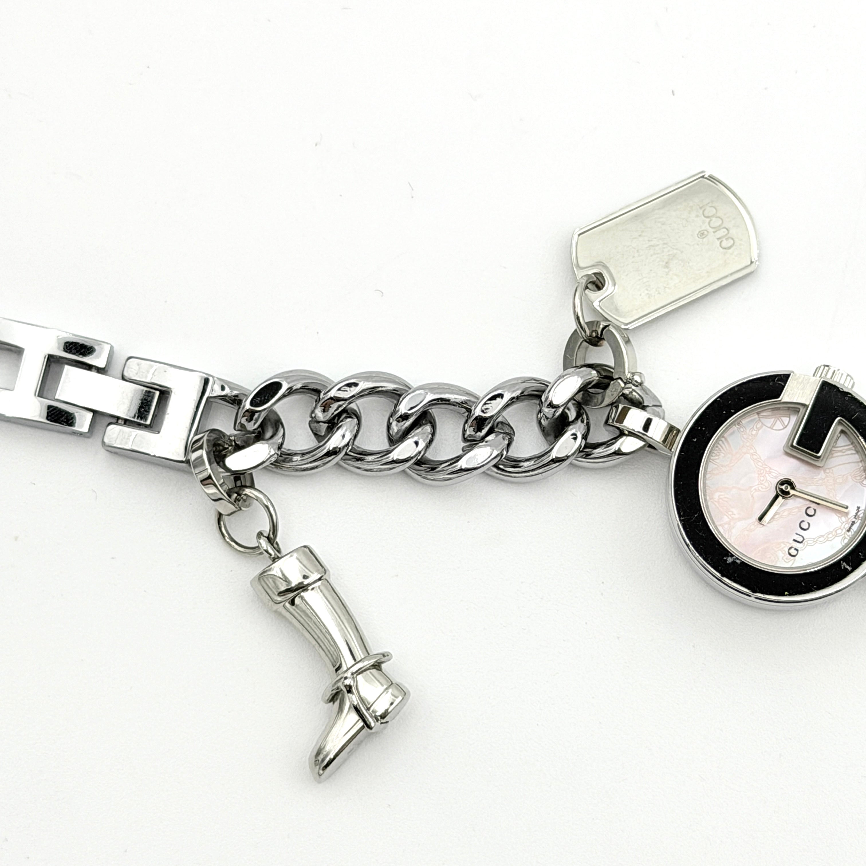 Gucci 107 G Charm Bracelet Watch with silver chunky chain and pink dial, styled on a brown cushion with original Gucci box.