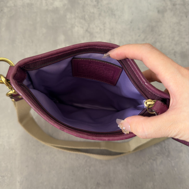 Coach Khaki Signature Crossbody Swing-pack in beige monogram canvas with purple leather trim, featuring an adjustable fabric strap and zippered top closure.