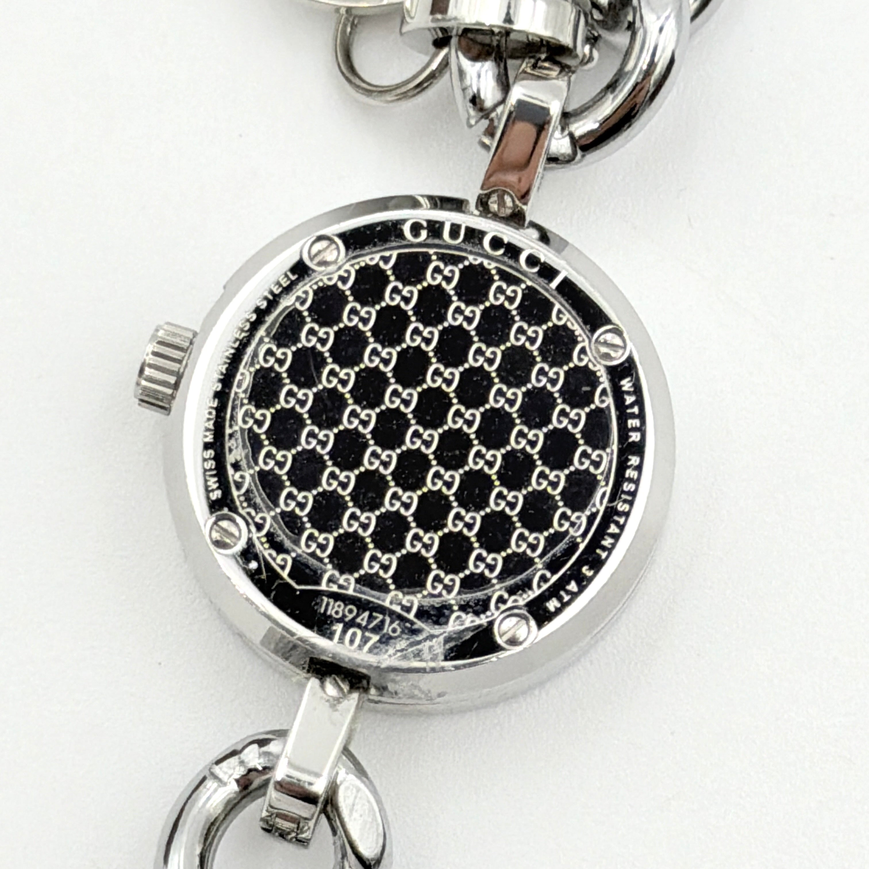 Gucci 107 G Charm Bracelet Watch with silver chunky chain and pink dial, styled on a brown cushion with original Gucci box.