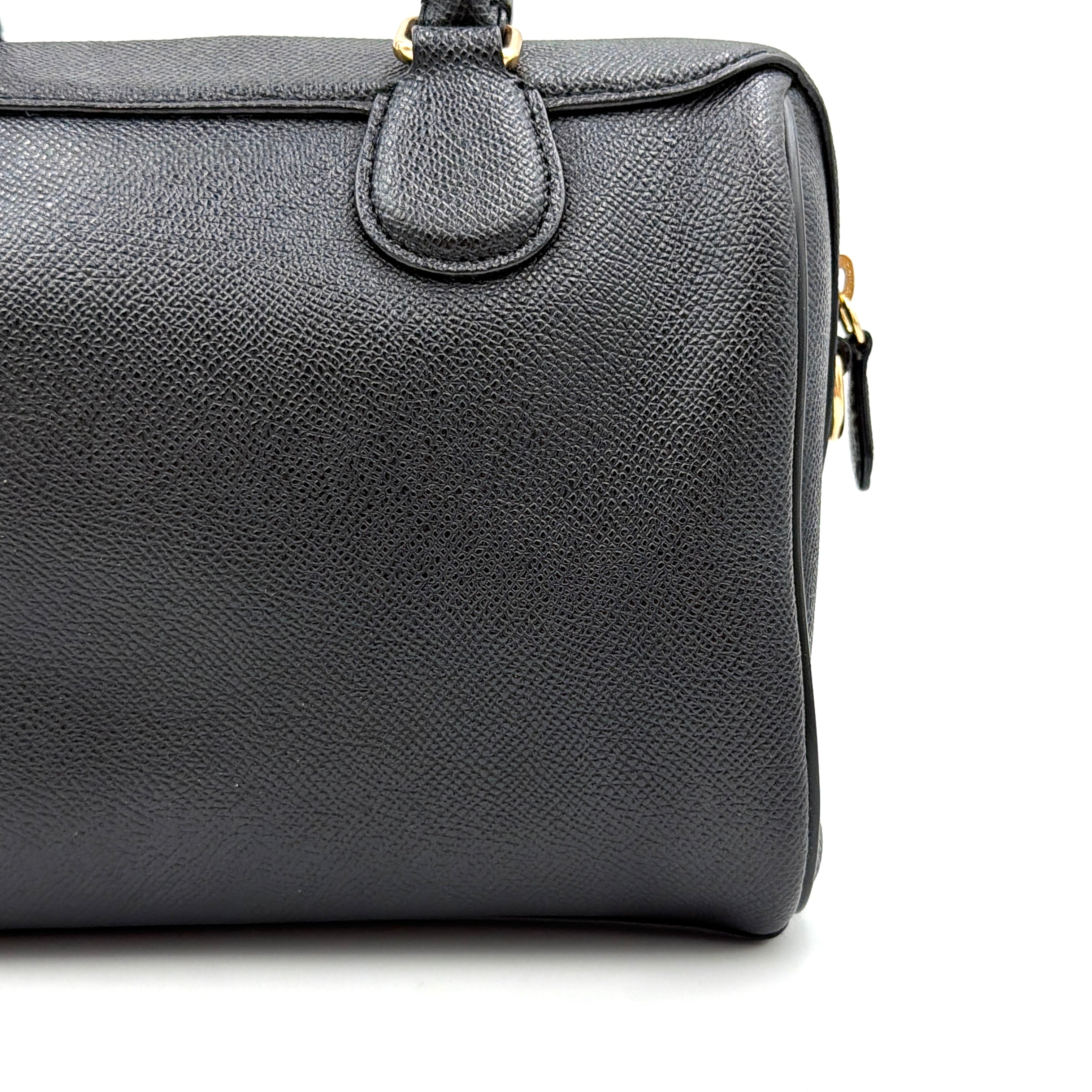 Coach Mini Bennett Boston Bag in black pebbled leather with gold hardware and detachable strap, styled against a clean backdrop.
