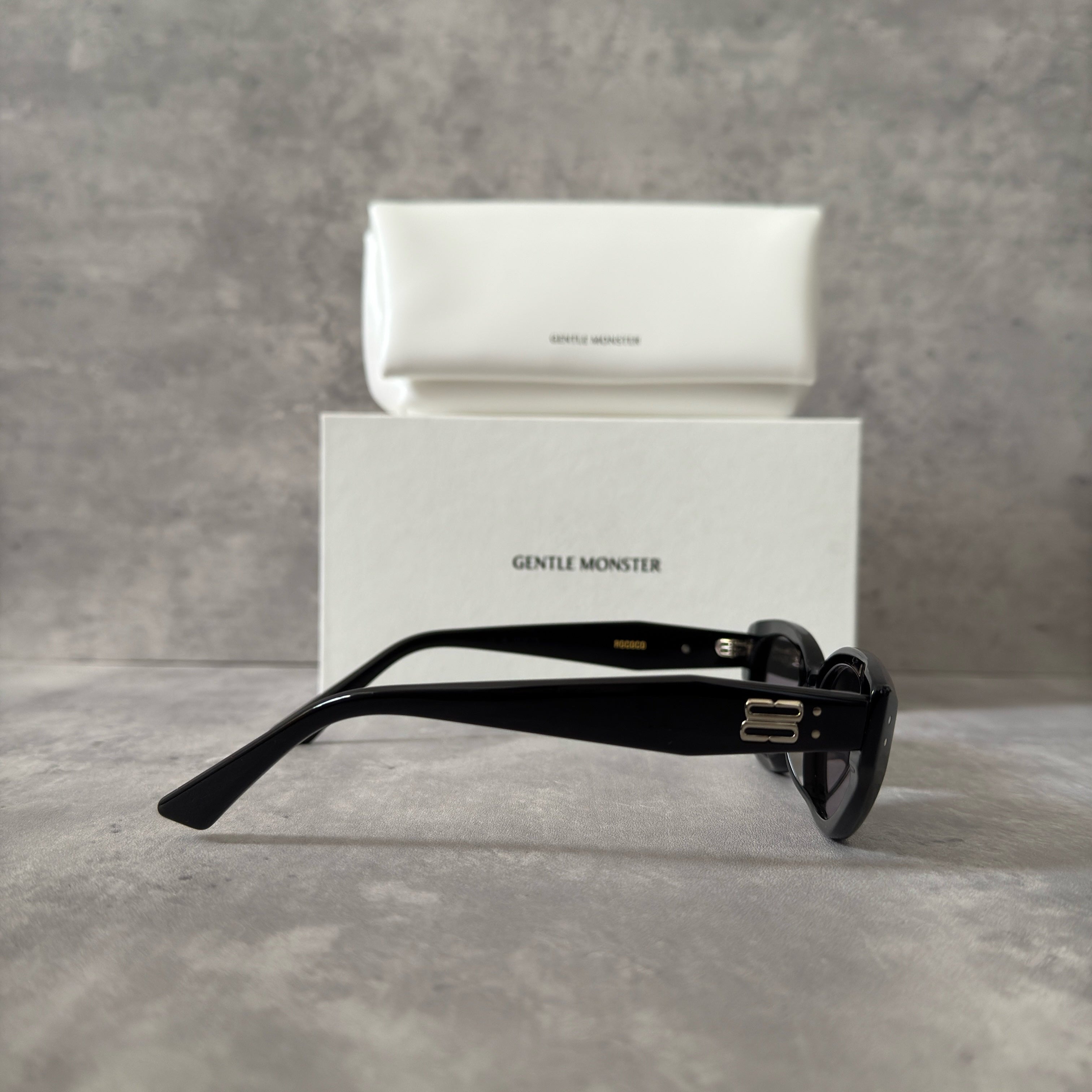 Gentle Monster ROCOCO - 01 black tinted sunglasses with a sleek acetate frame and gold-tone logo on temples.