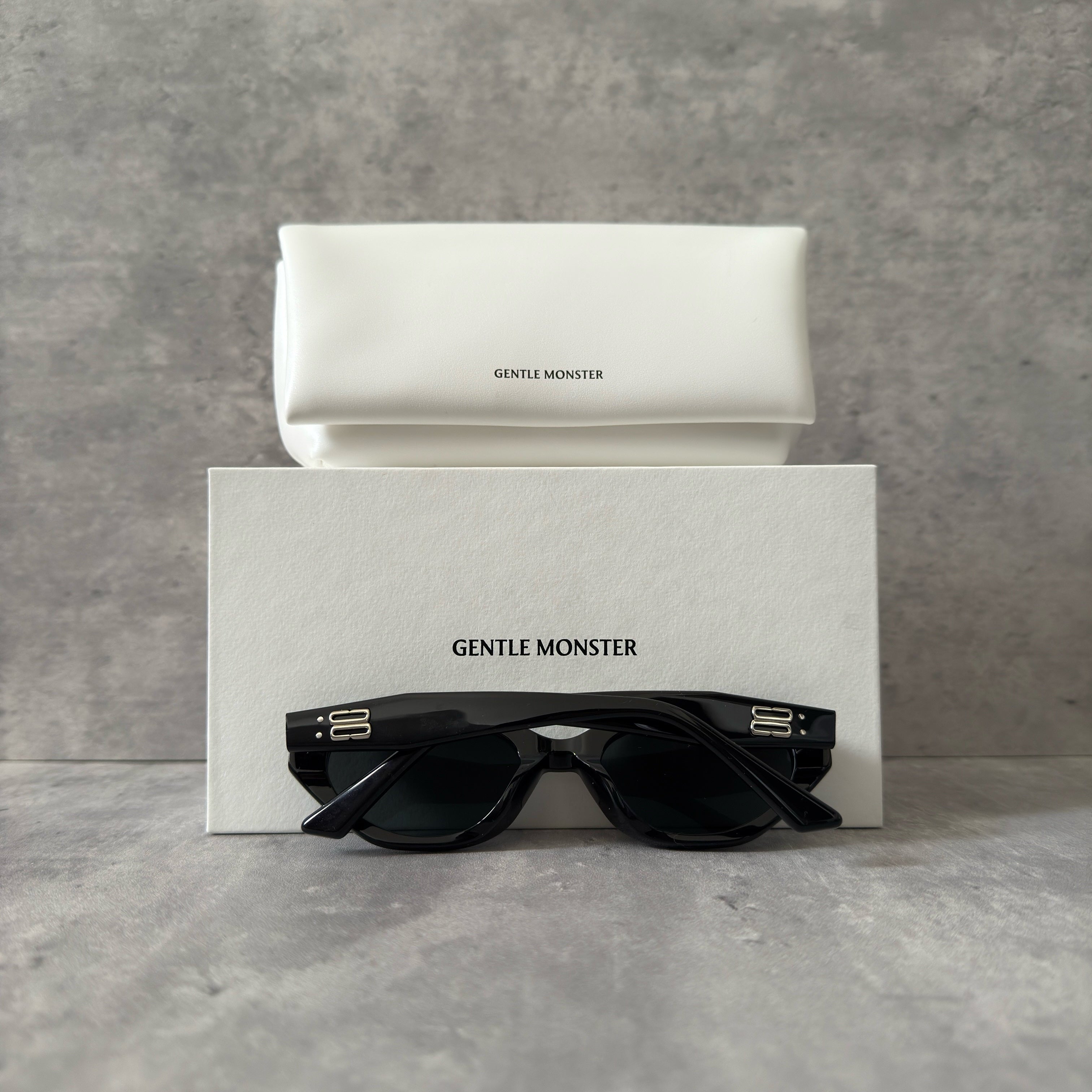 Gentle Monster ROCOCO - 01 black tinted sunglasses with a sleek acetate frame and gold-tone logo on temples.