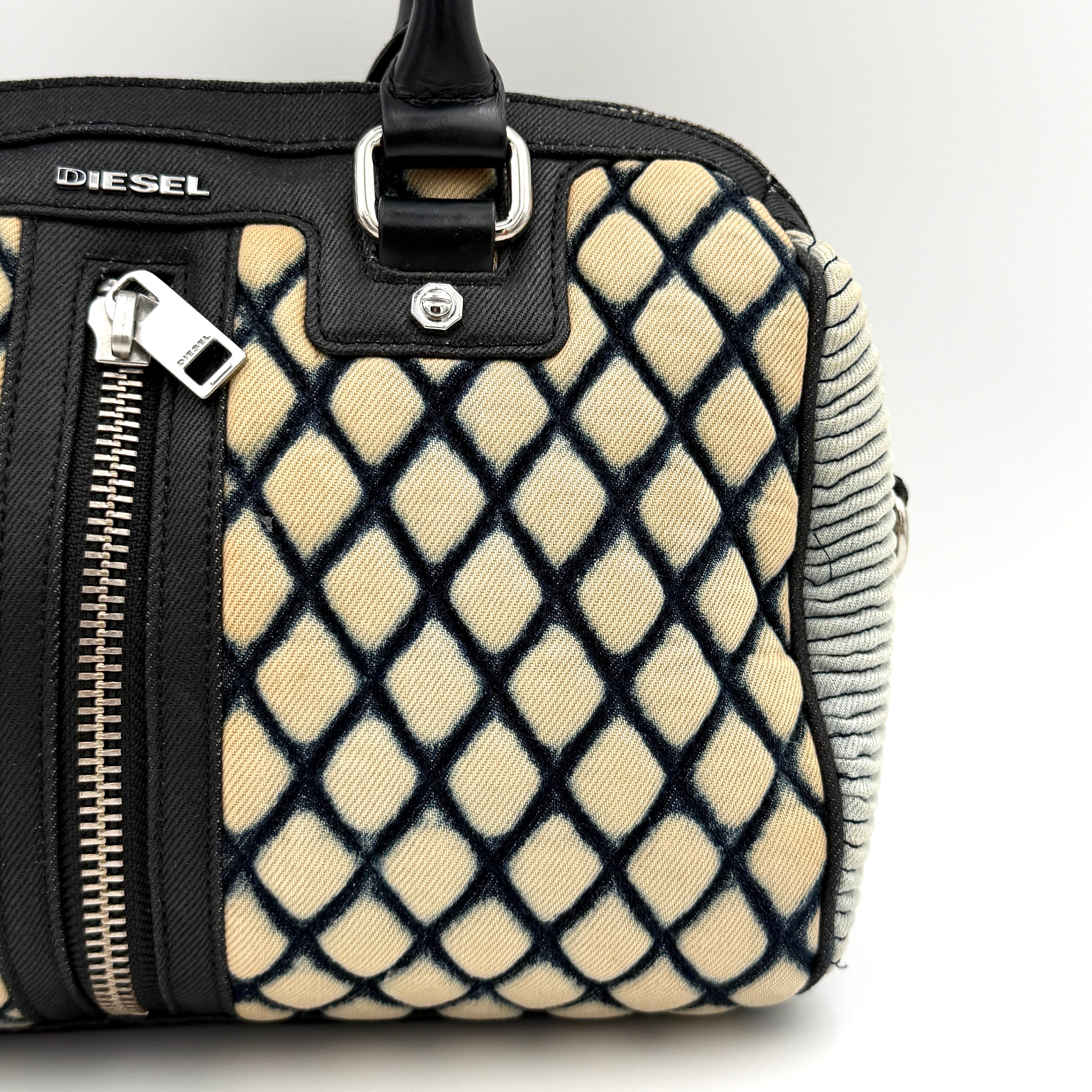 Diesel 2Way Boston Handbag in cream canvas with black velvet-effect lattice, dual leather handles, and detachable strap displayed in front.