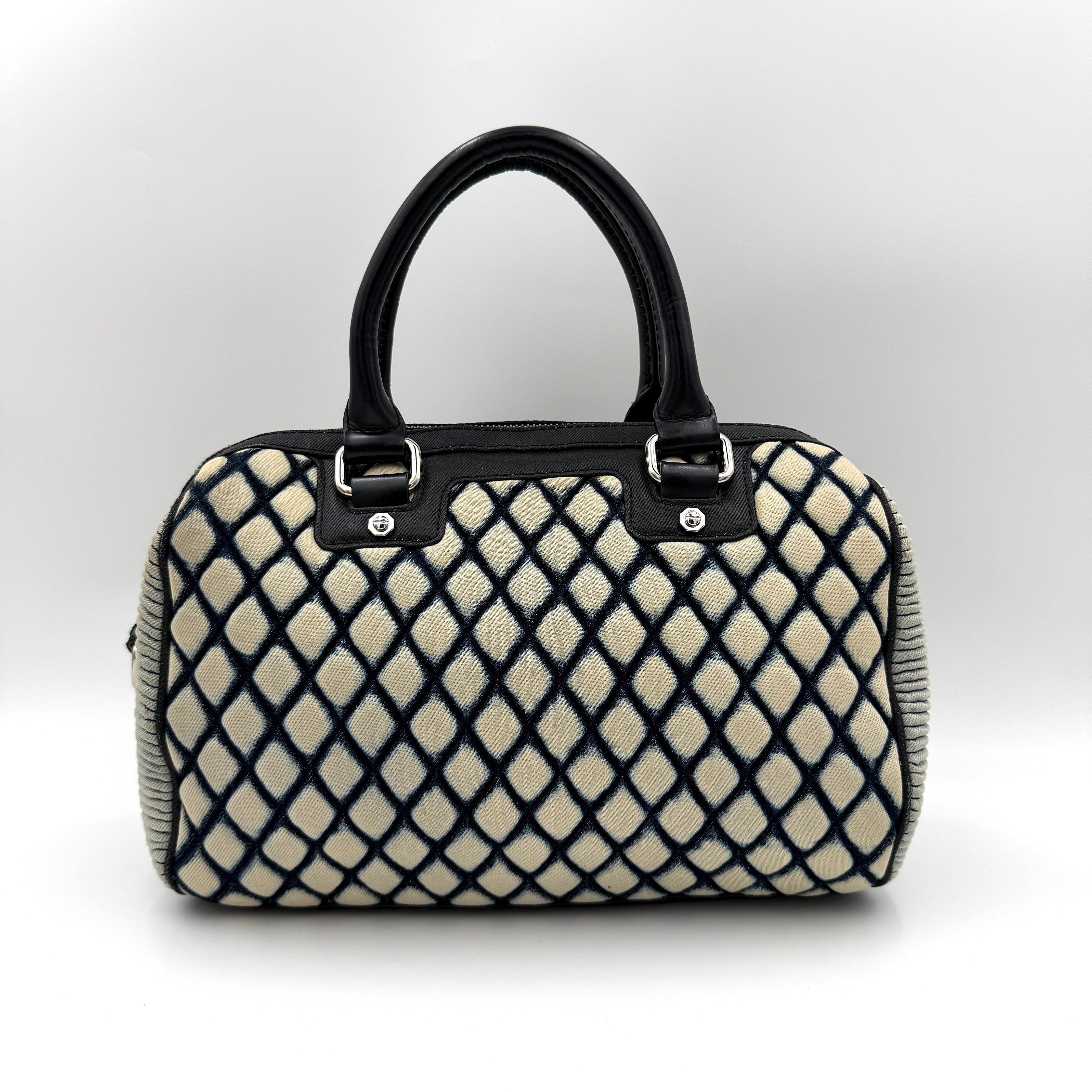 Diesel 2Way Boston Handbag in cream canvas with black velvet-effect lattice, dual leather handles, and detachable strap displayed in front.