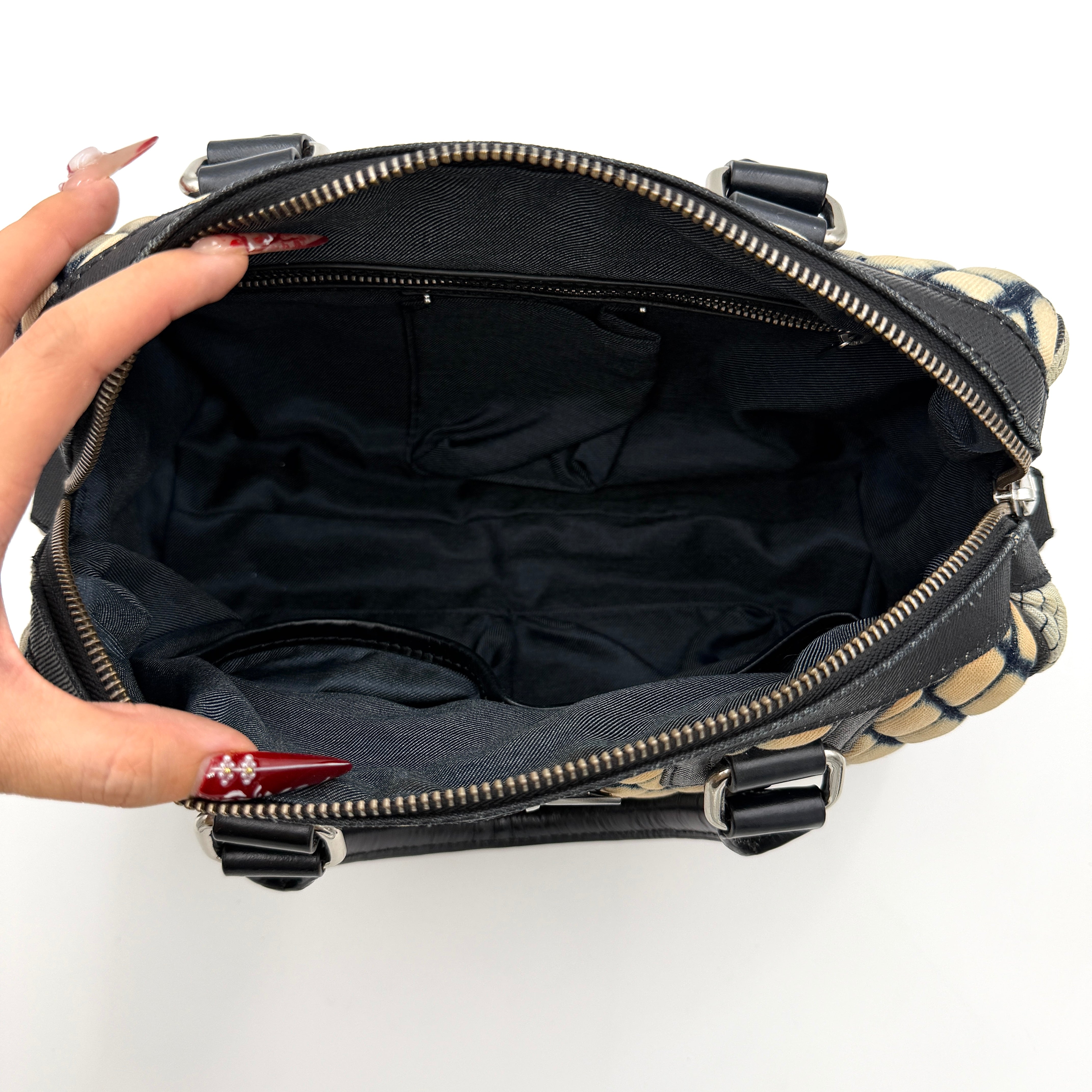 Diesel 2Way Boston Handbag in cream canvas with black velvet-effect lattice, dual leather handles, and detachable strap displayed in front.