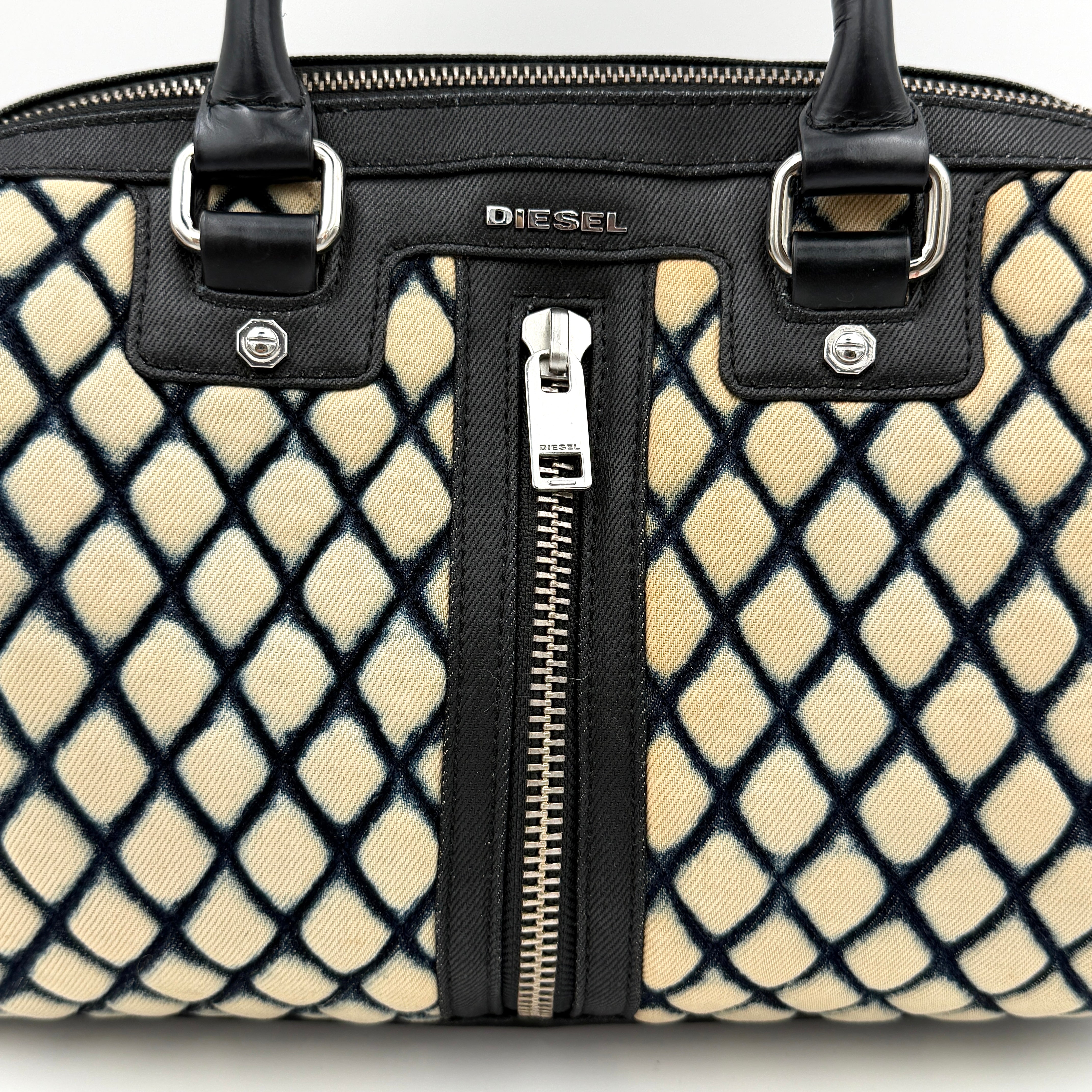 Diesel 2Way Boston Handbag in cream canvas with black velvet-effect lattice, dual leather handles, and detachable strap displayed in front.