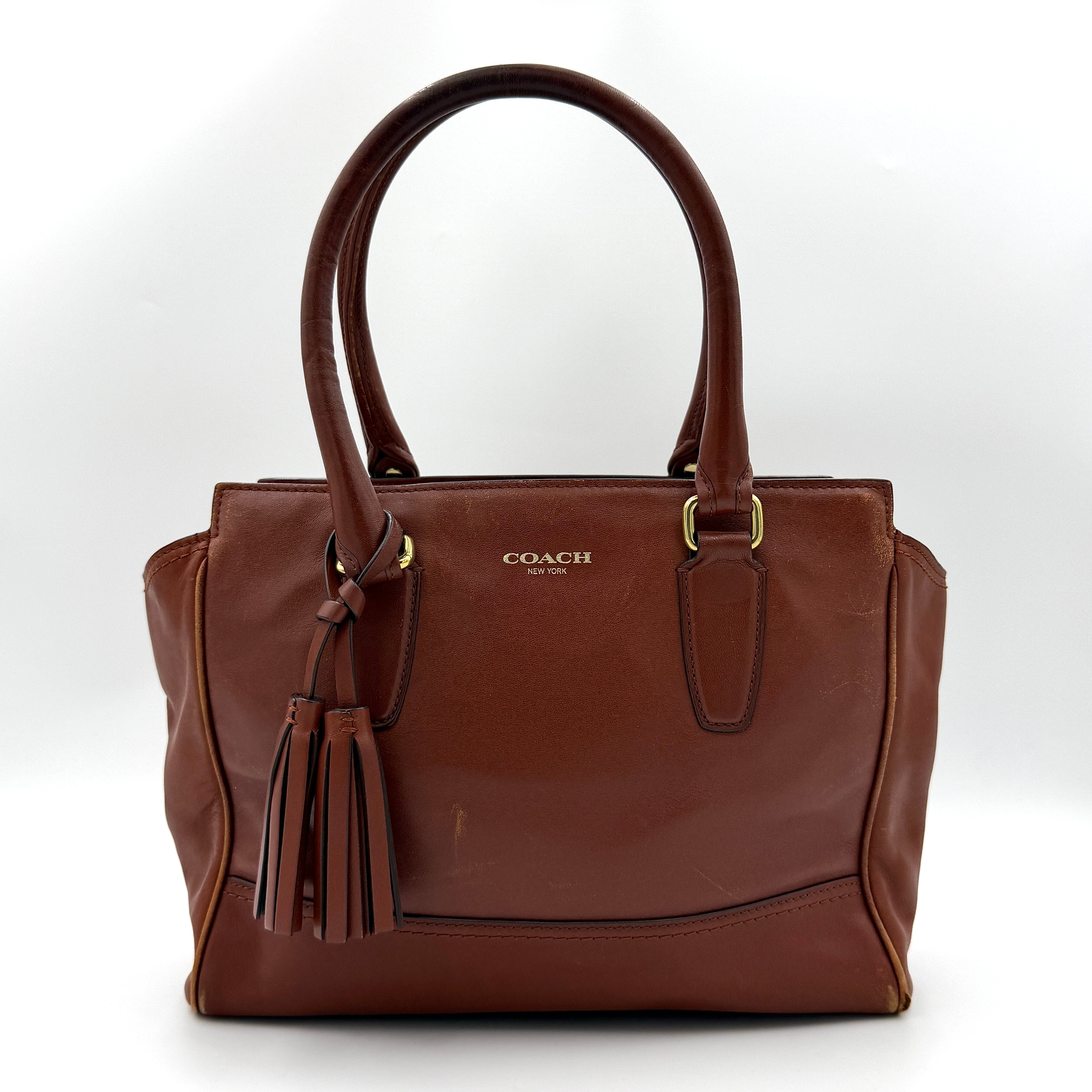 Coach Legacy Candace Carryall in smooth brown leather with gold hardware, rolled handles, and signature tassel accents.
