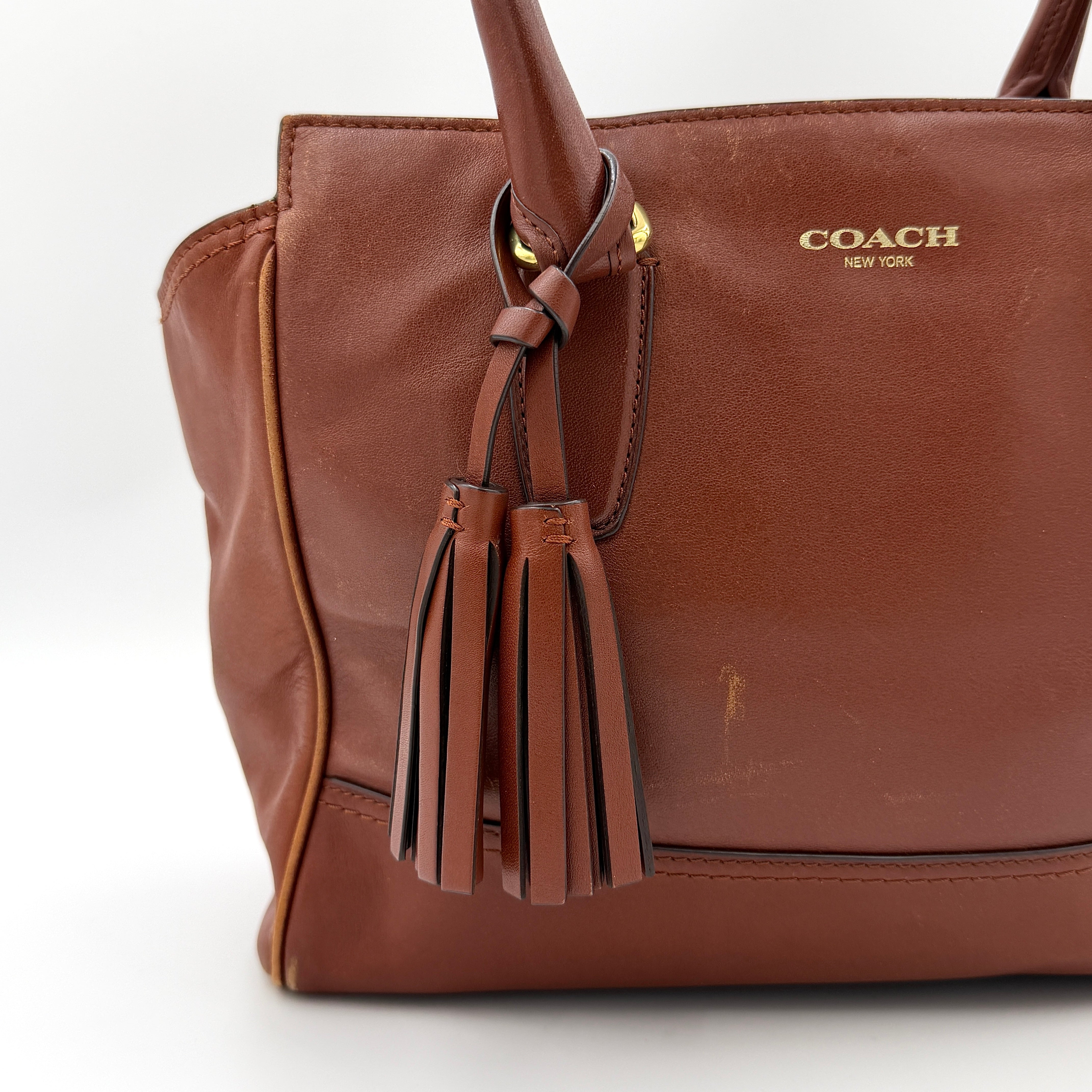 Coach Legacy Candace Carryall in smooth brown leather with gold hardware, rolled handles, and signature tassel accents.