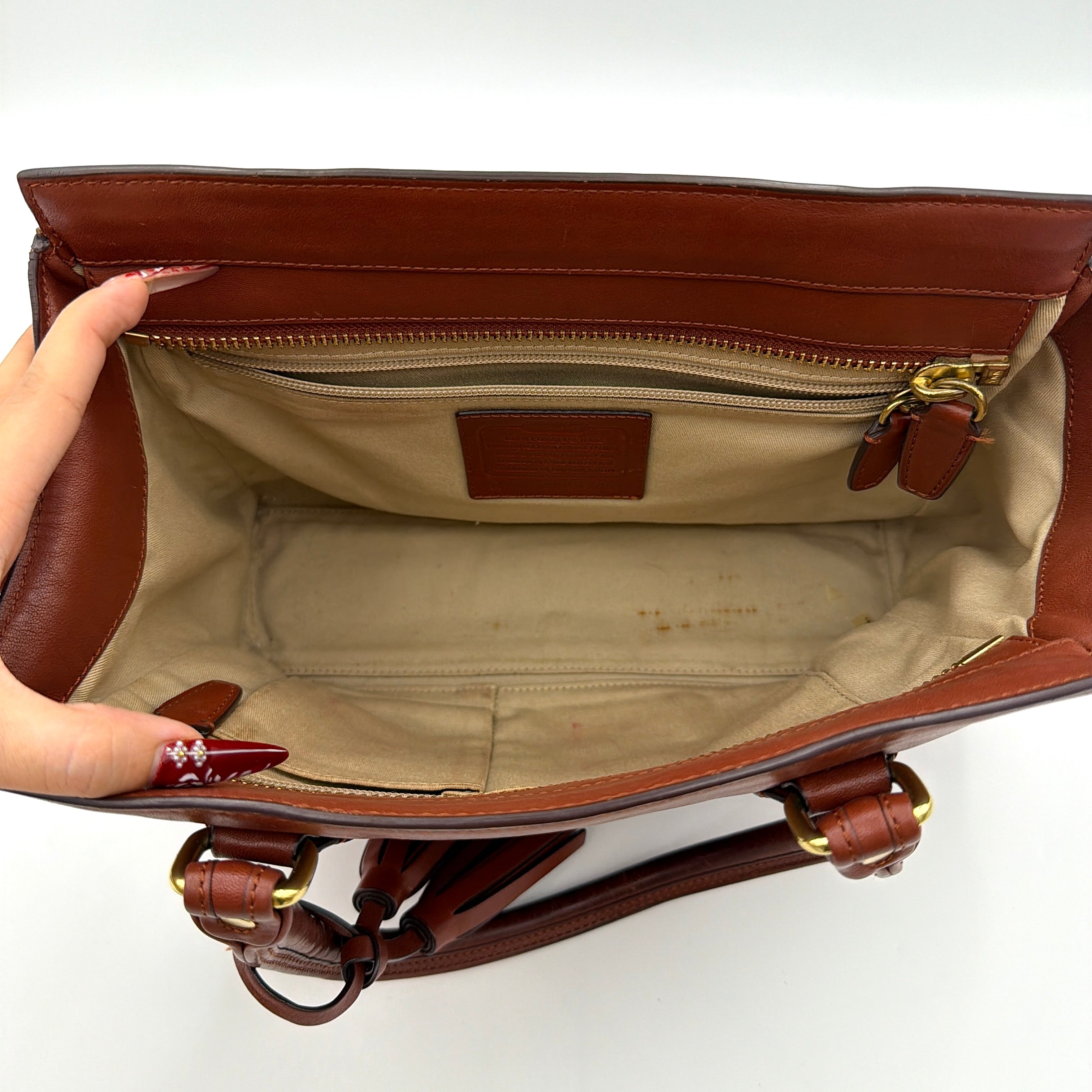 Coach Legacy Candace Carryall in smooth brown leather with gold hardware, rolled handles, and signature tassel accents.