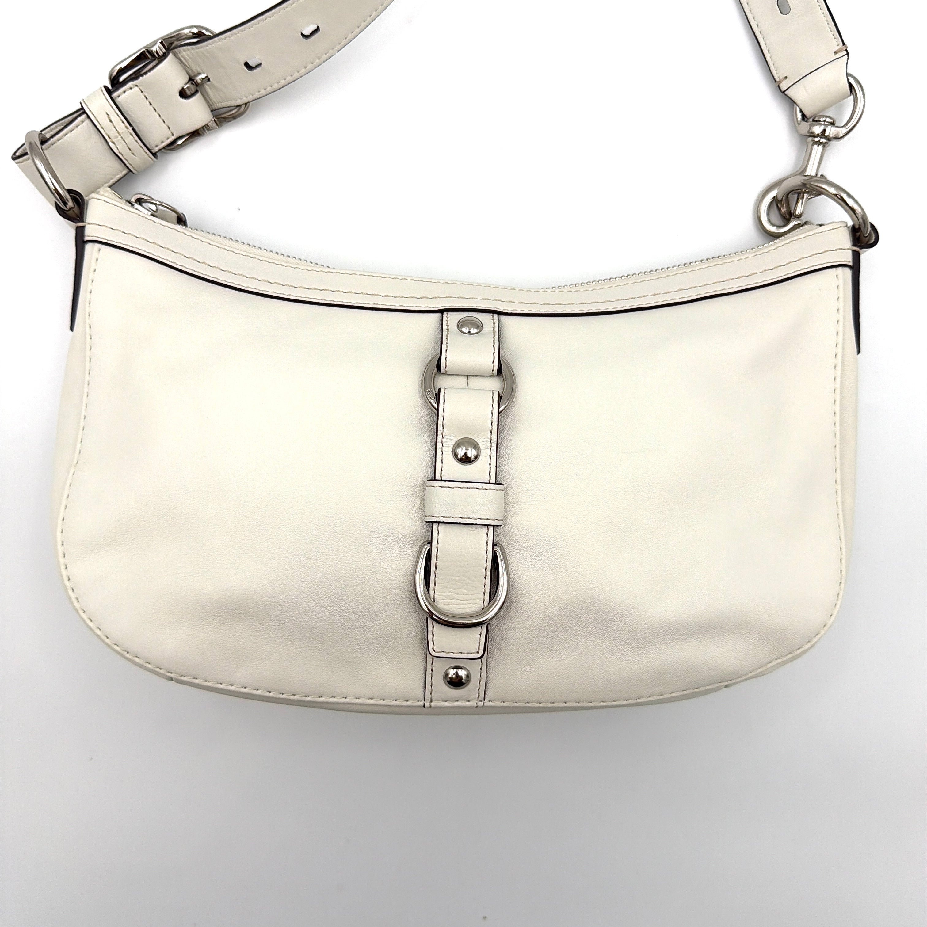 Coach 2Way Buckle Shoulder Bag in smooth ivory leather with silver-tone hardware and an adjustable strap, styled against a white background.