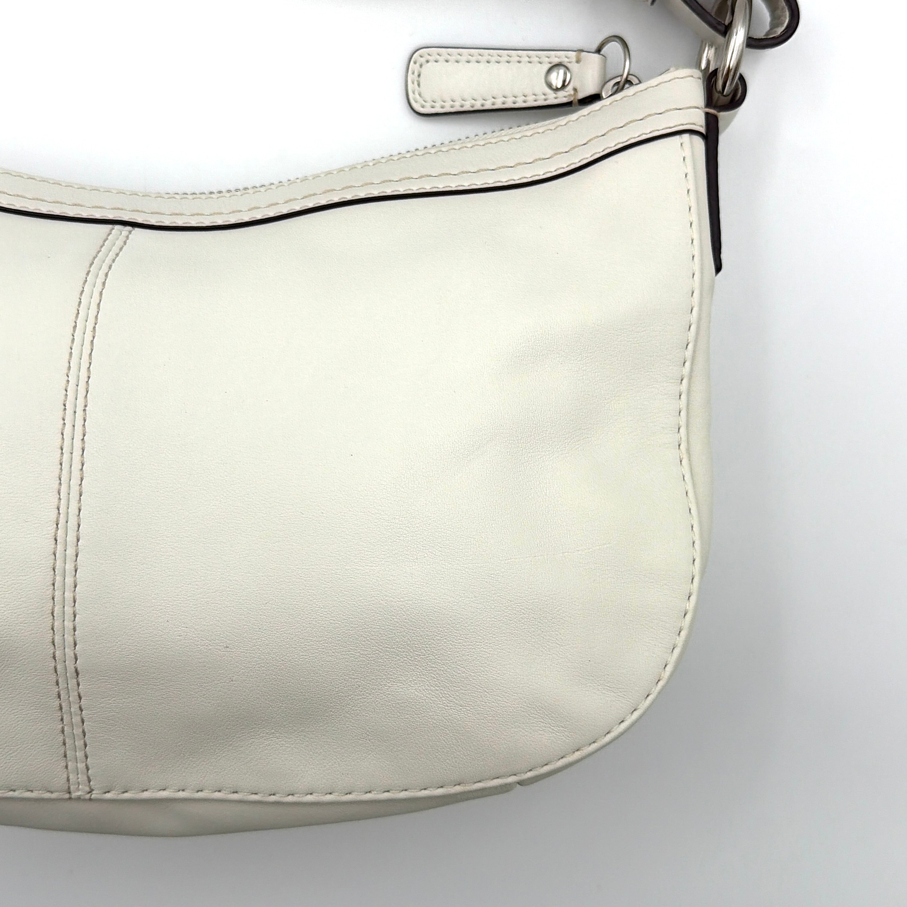 Coach 2Way Buckle Shoulder Bag in smooth ivory leather with silver-tone hardware and an adjustable strap, styled against a white background.
