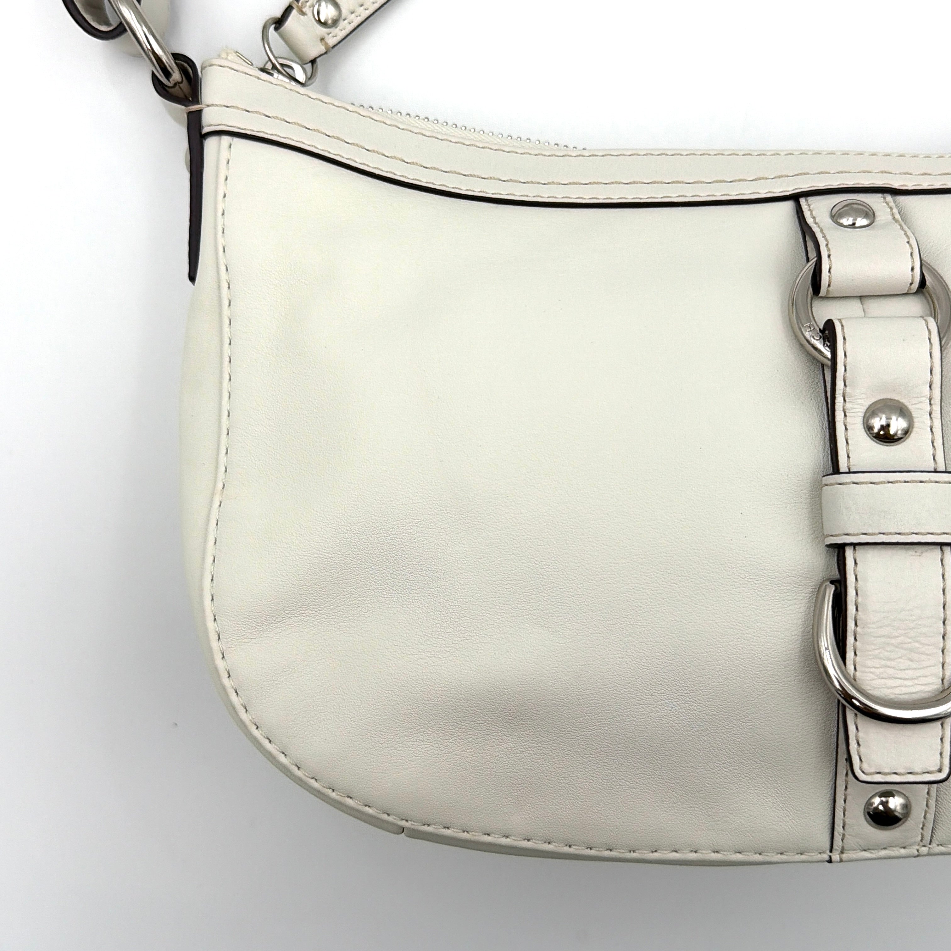 Coach 2Way Buckle Shoulder Bag in smooth ivory leather with silver-tone hardware and an adjustable strap, styled against a white background.