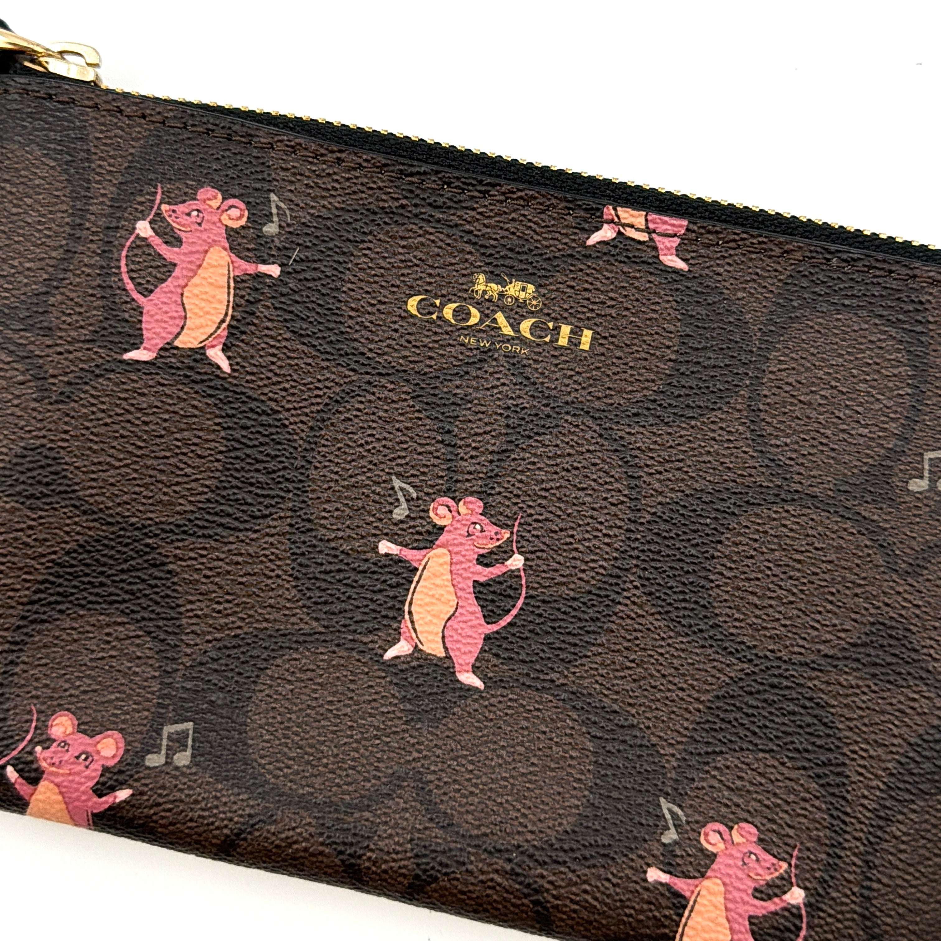 Coach Party Mouse Corner Zip Wristlet in brown canvas, featuring playful pink mouse illustrations and a black leather wrist strap.
