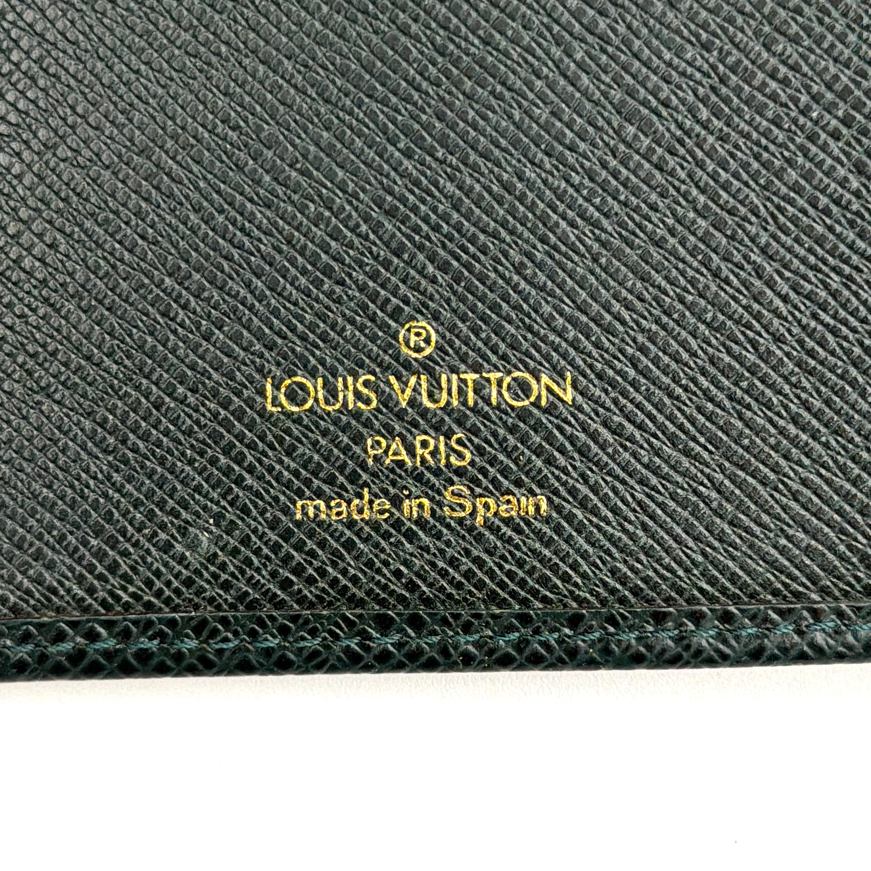 A Louis Vuitton Taiga Brazza Wallet in dark green, showcasing fine cross-grain leather texture and the understated LV monogram debossed on the front.
