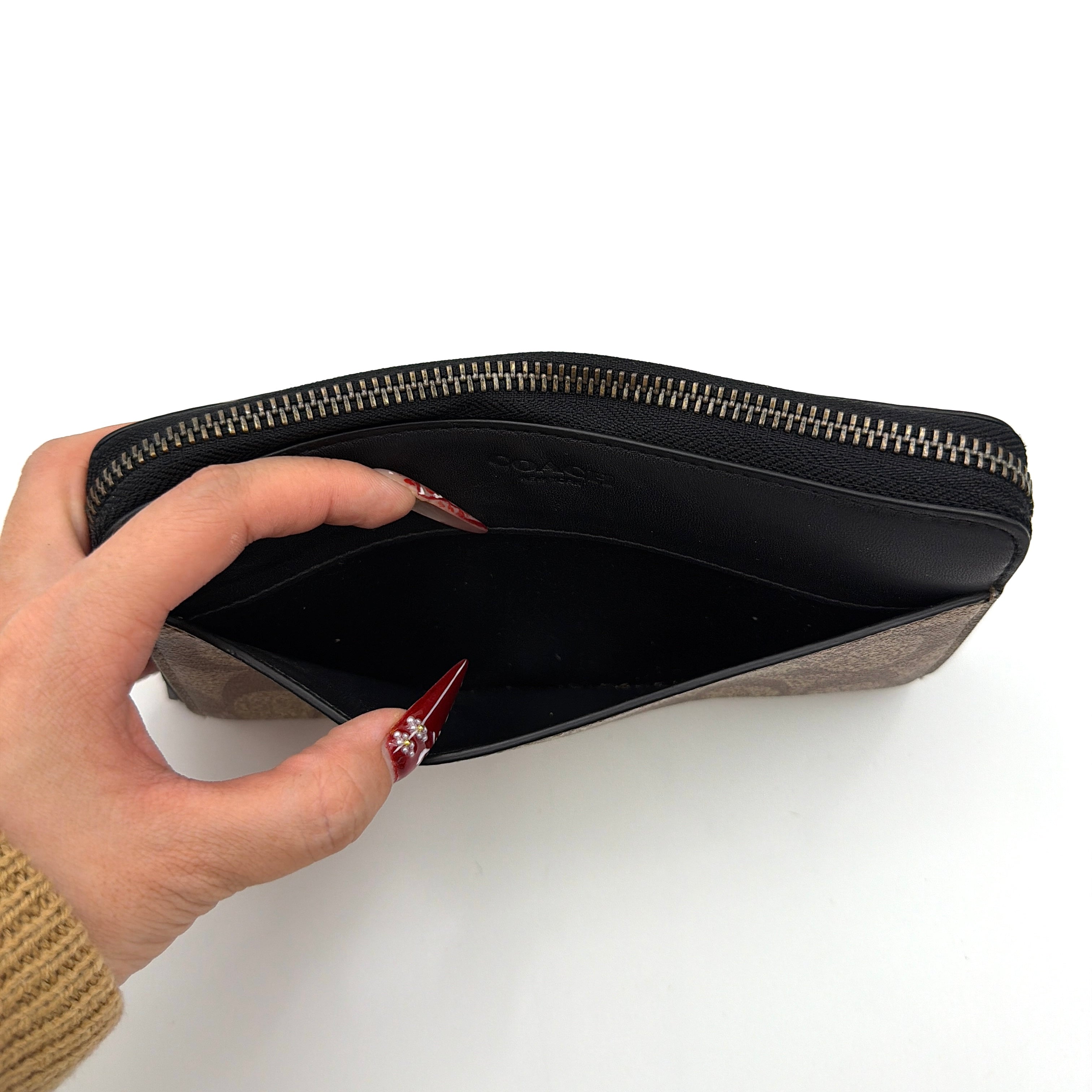 Coach Signature Accordion Long Wallet in beige and black canvas with black leather trim, featuring zip-around closure.